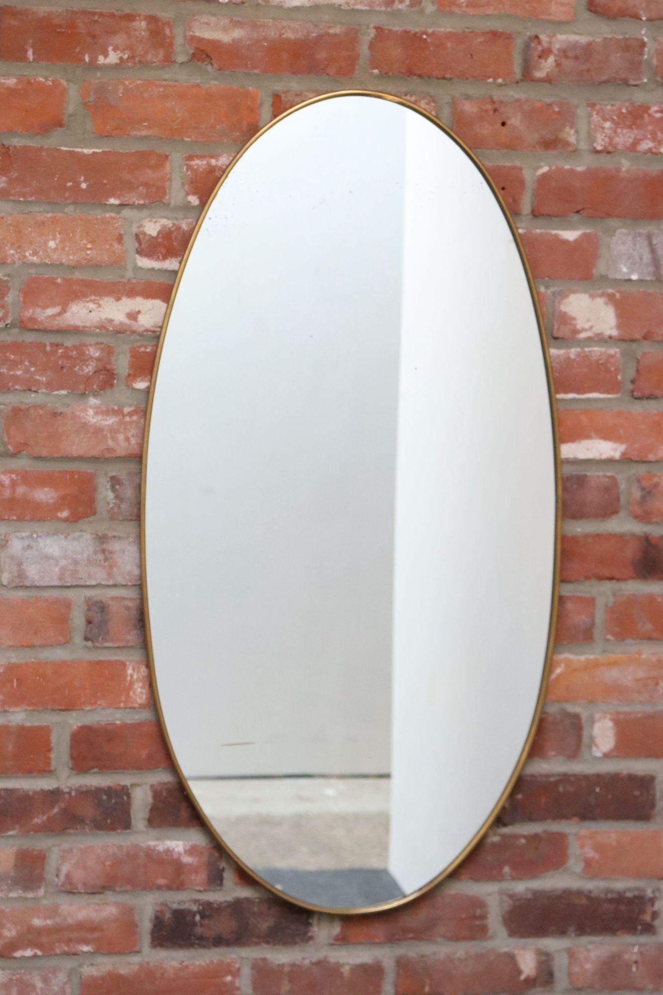 Miroir mural elliptique/ovale moderniste italien d'après Gio Ponti, composé de verre inséré dans un cadre en laiton (vers les années 1960, Italie).
Dans l'ensemble, en bon état, vintage. Le laiton poli présente une patine naturelle et une usure