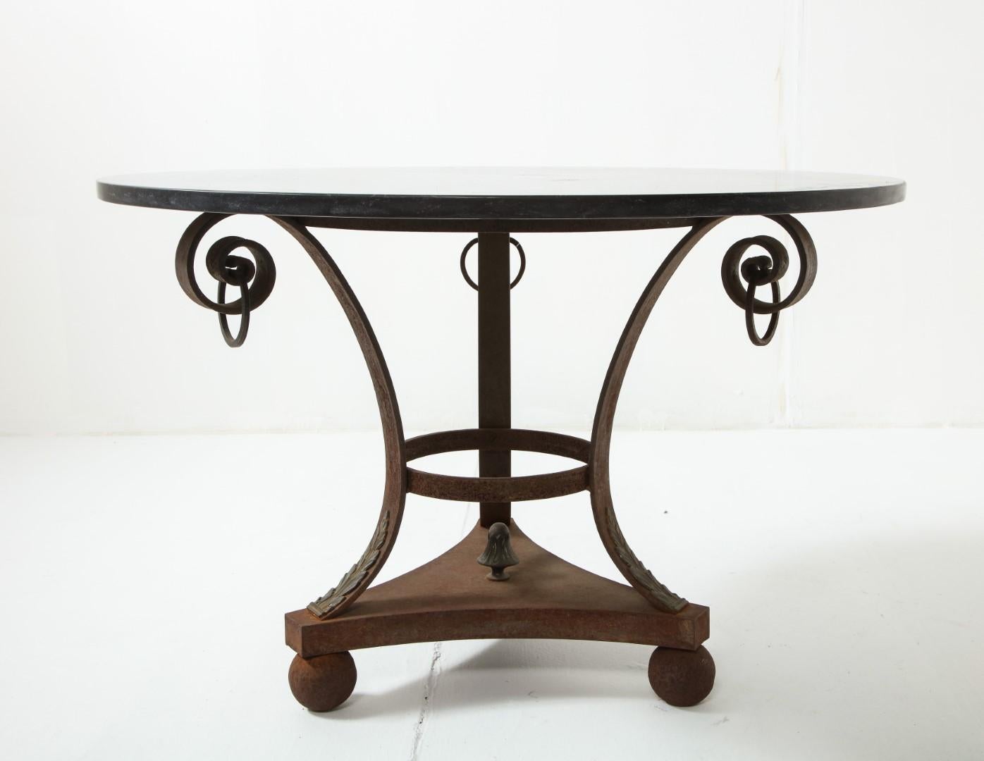 Vintage 20th century Italian Empire style outdoor coffee table with black marble top. Wrought iron base is rusted from outdoor use, scroll and ring details, three ball feet.
