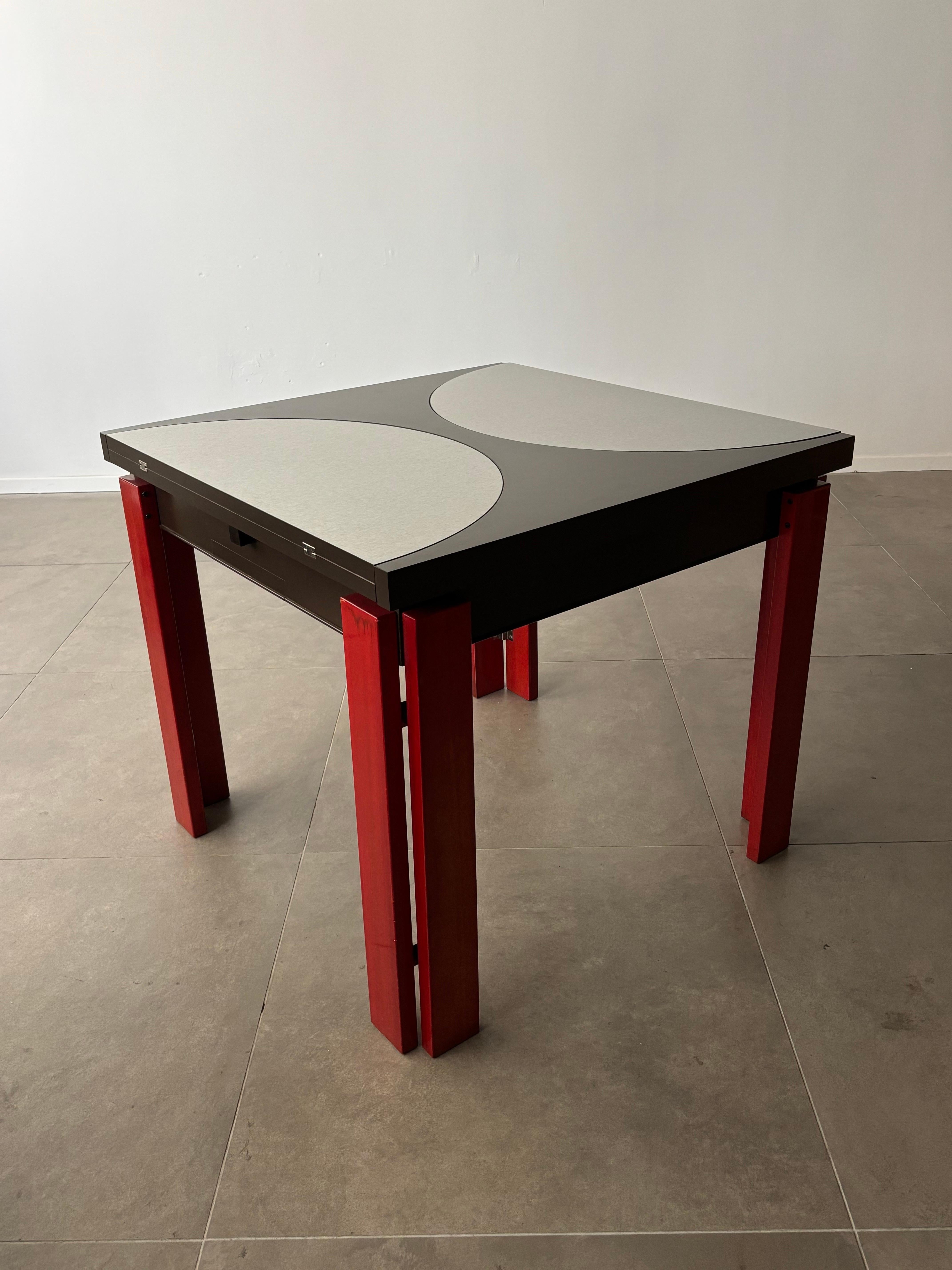 Cette table de salle à manger extensible italienne vintage des années 1970 présente un design frappant et ingénieux. Le plateau de la table présente deux incrustations en demi-cercle en acier inoxydable positionnées dans des directions opposées, ce