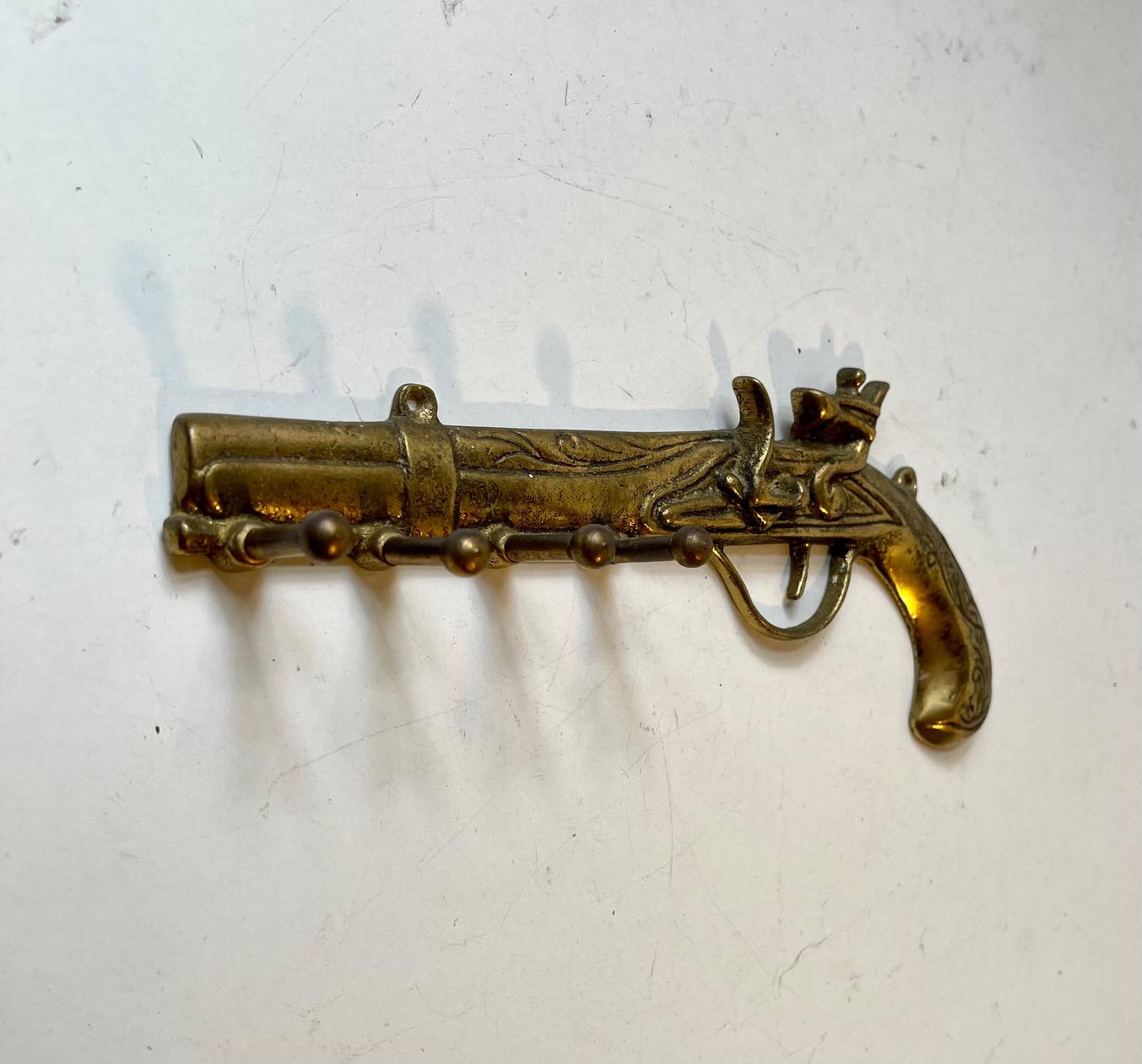 Unusual wall mounted key holder in the shape of an antique flintlock pistol. Its made from cast solid brass and features 4 hooks for your keys. It was made in Italy during the 1970s and brought home to Denmark by a tourist. Measurements: W/L: 22 cm,
