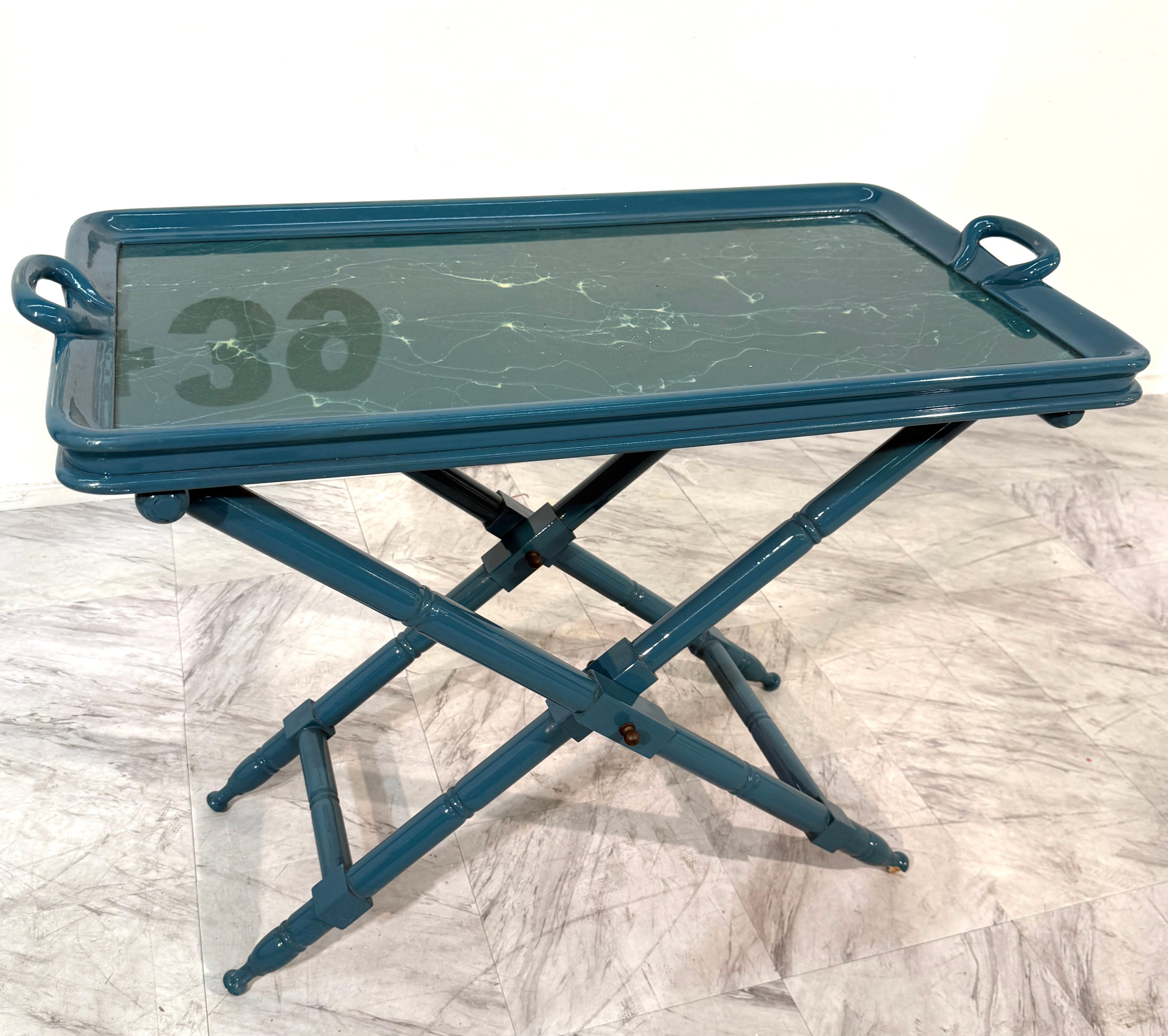 Eleganter, in Italien handgefertigter, klappbarer Vintage-Tisch. Das Stück hat einen lackierten Holzrahmen in sattem Teal und eine abnehmbare Servierplatte. Das Tablett selbst hat eine schöne grüne Oberfläche aus Marmorimitat, die durch natürliche,