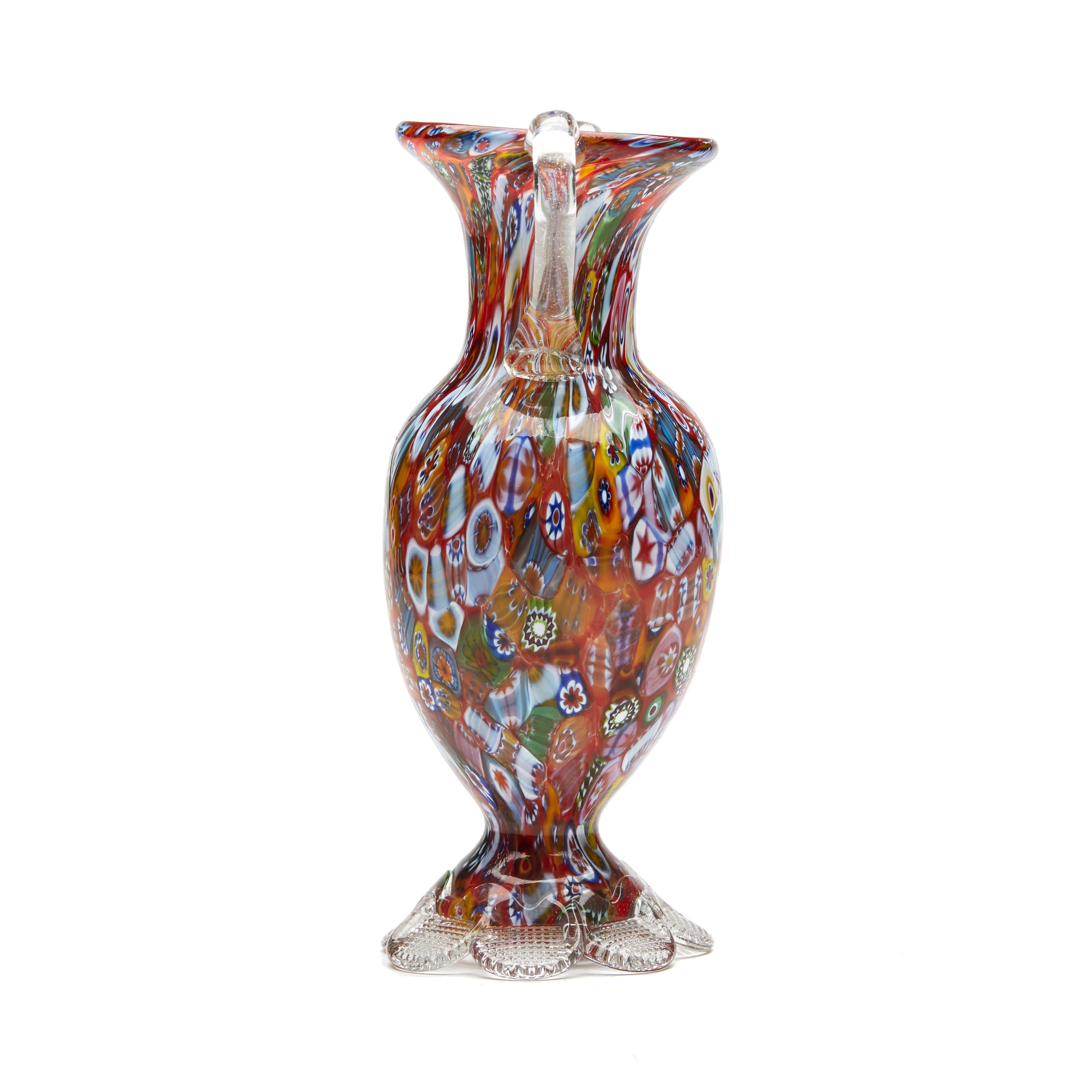 A stylish vintage Italian Murano twin handled millefiori vase by Fratelli & Toso. The hand blown glass vase stands on a clear glass petal shaped foot each impressed with a grid pattern from beneath supporting a bulbous shaped body with a narrowing