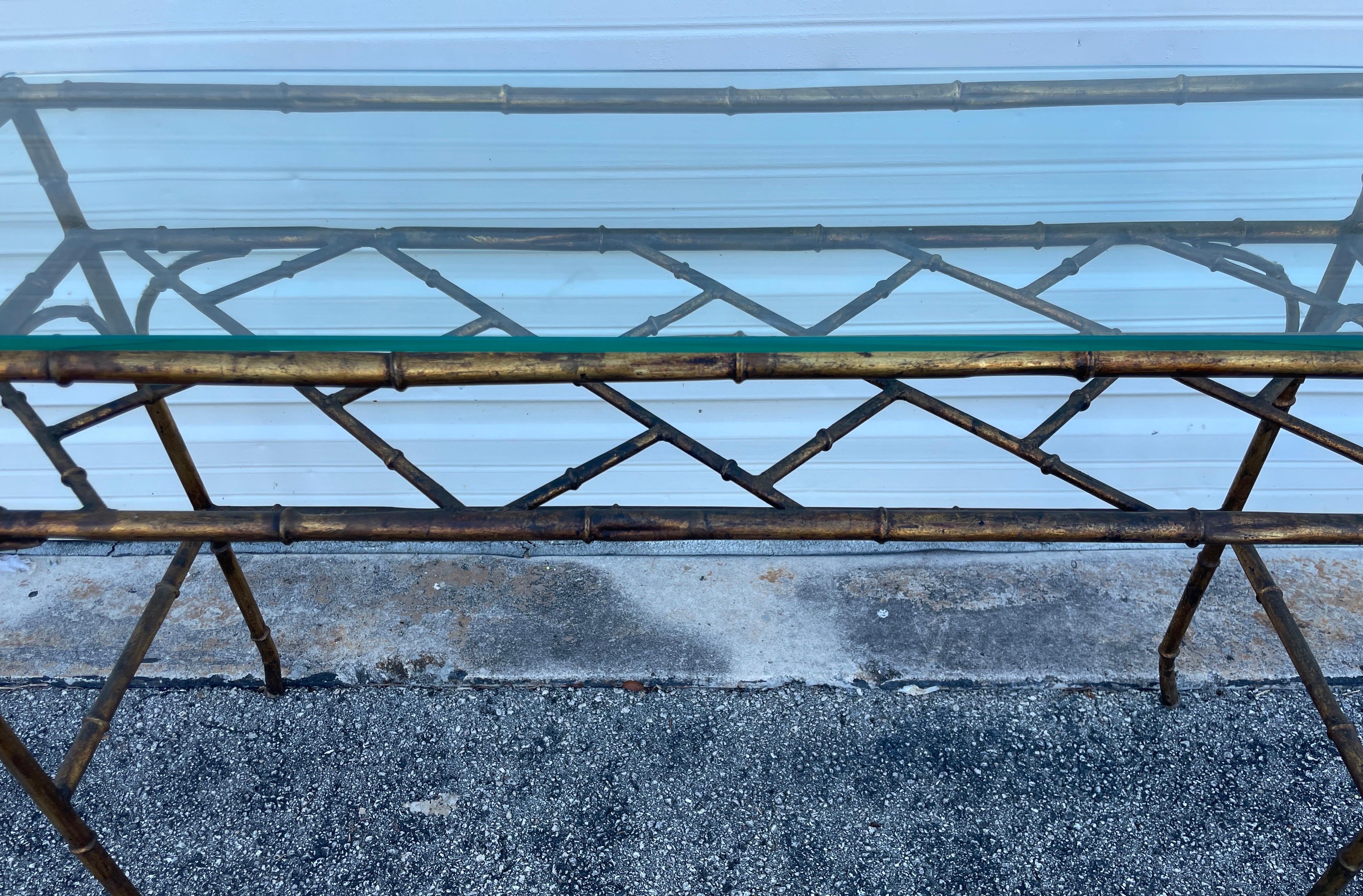 Vintage gilded metal faux bamboo console table with glass top. Front is open to fit a bench underneath. Fretwork shelf under the main glass top.