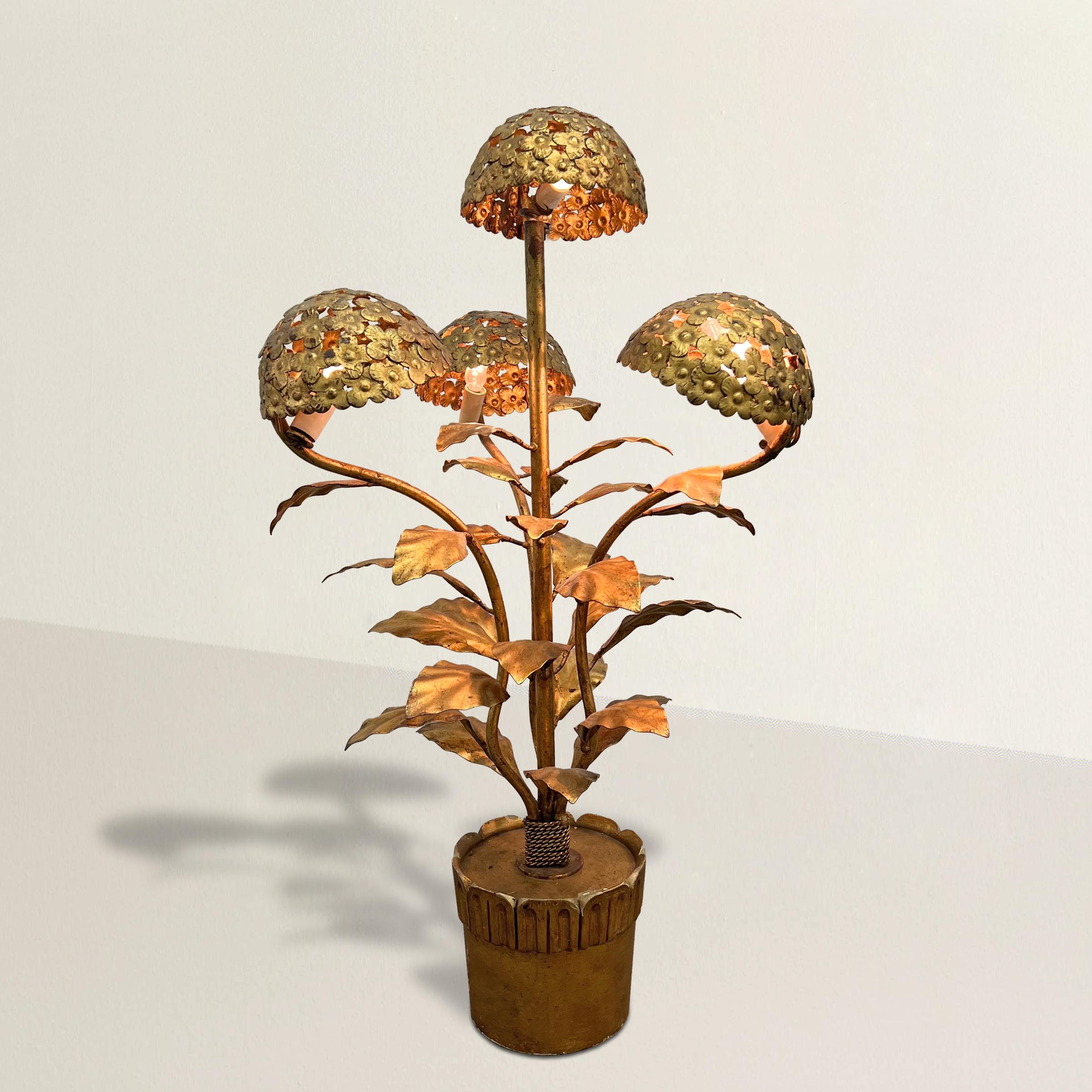 A whimsical and playful Italian mid-20th century gilt steel table lamp in the form of a potted hydrangea plant with three arms surrounding a central stem, all with large mop-head hydrangea blossoms that light from below, and with myriad leaves
