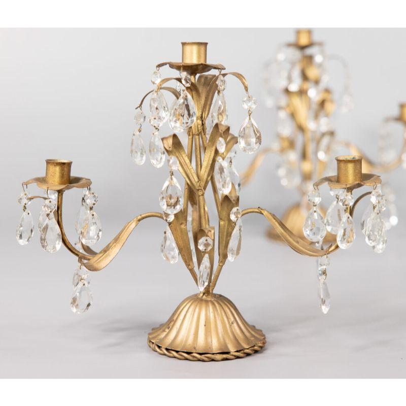 A gorgeous pair of mid-century Italian gilded tole and crystals candelabras. These stunning candelabras are accented with beautiful teardrop crystals, scrolling leaves, and a fluted base in a lovely gilt patina. Add a touch of Italy to your holiday