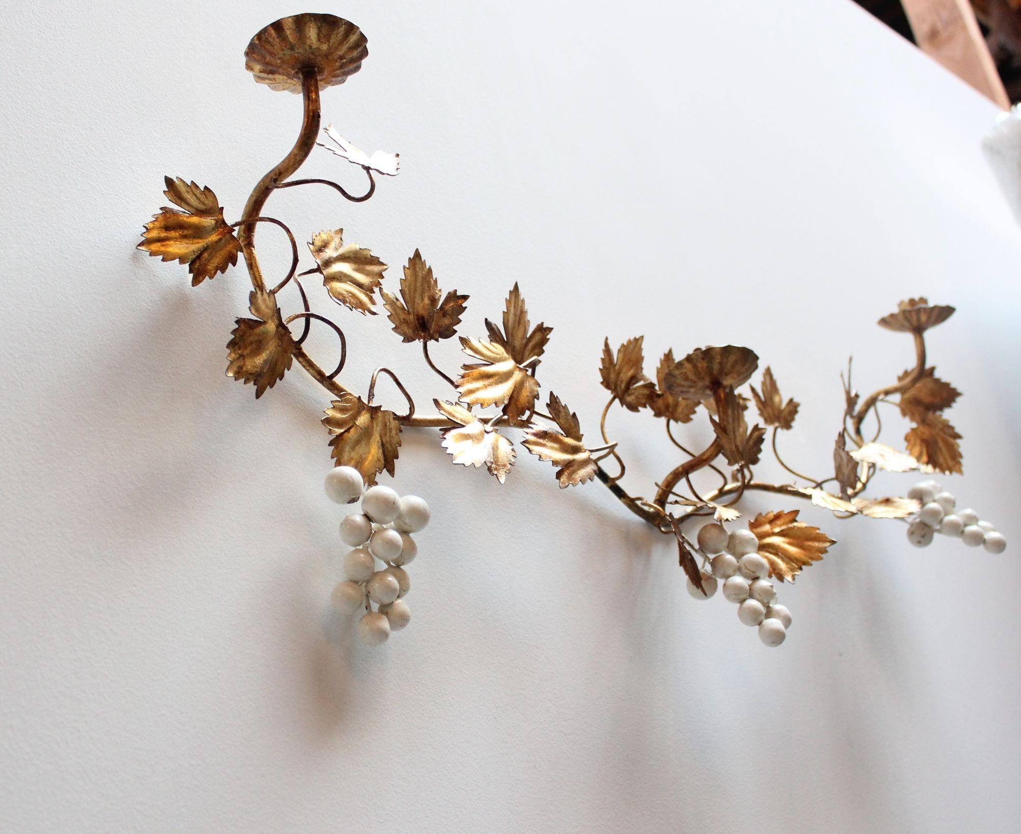 Applique a tripla candela italiana in tole dorata con motivo di foglie d'uva e uva (ca. 1970, Italia).
Patina naturale presente con macchie di doratura e perdita di vernice, come mostrato. Rimane in ottime condizioni vintage. 
Conserva l'etichetta