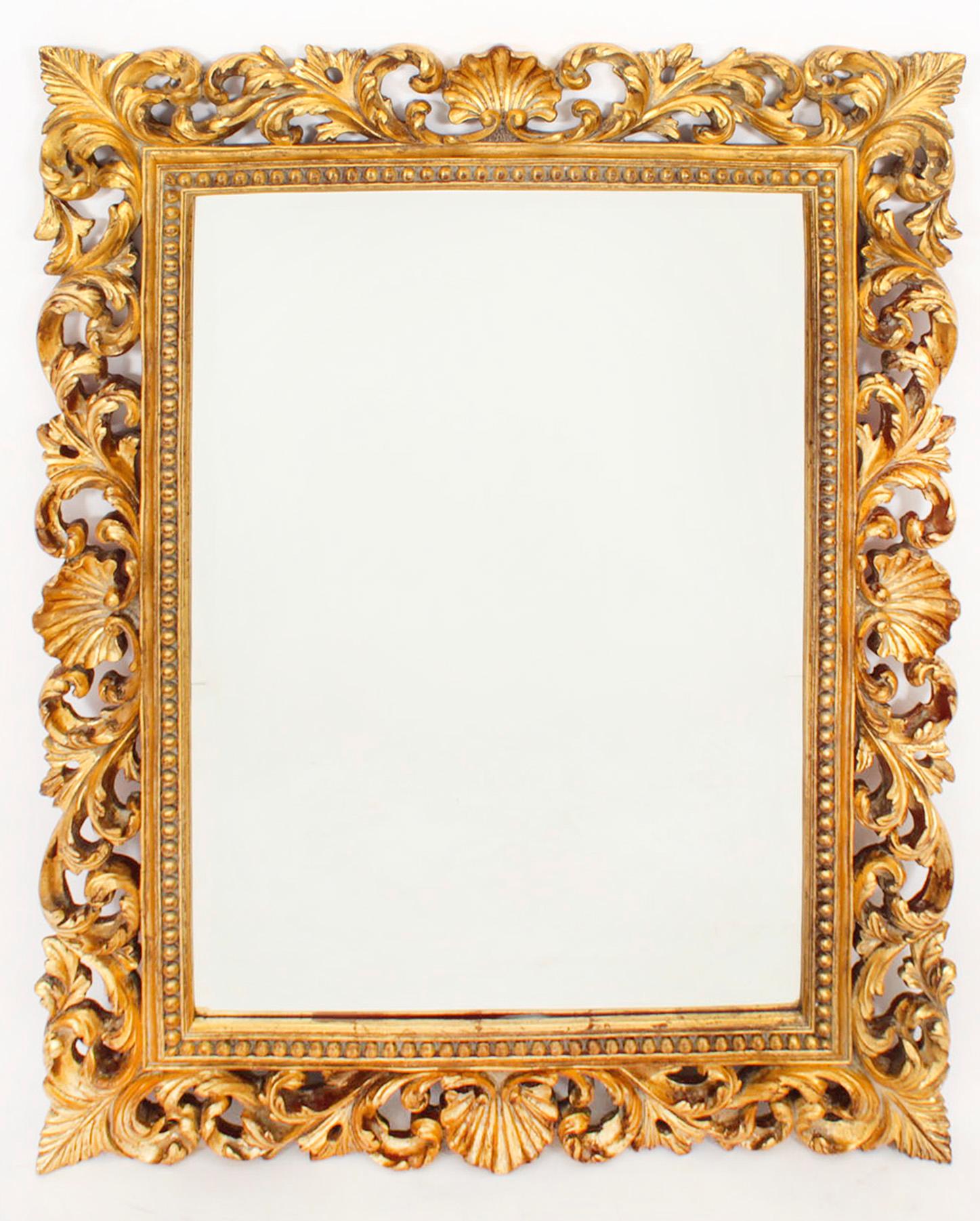 A highly decorative Florentine  overmantle mirror, mid 20th Century in date. 

This rectangular mirror consists of a  giltwood frame with an arrow beaded border and scrolling acanthus leaf foliate decoration in high relief, it can be hung portrait