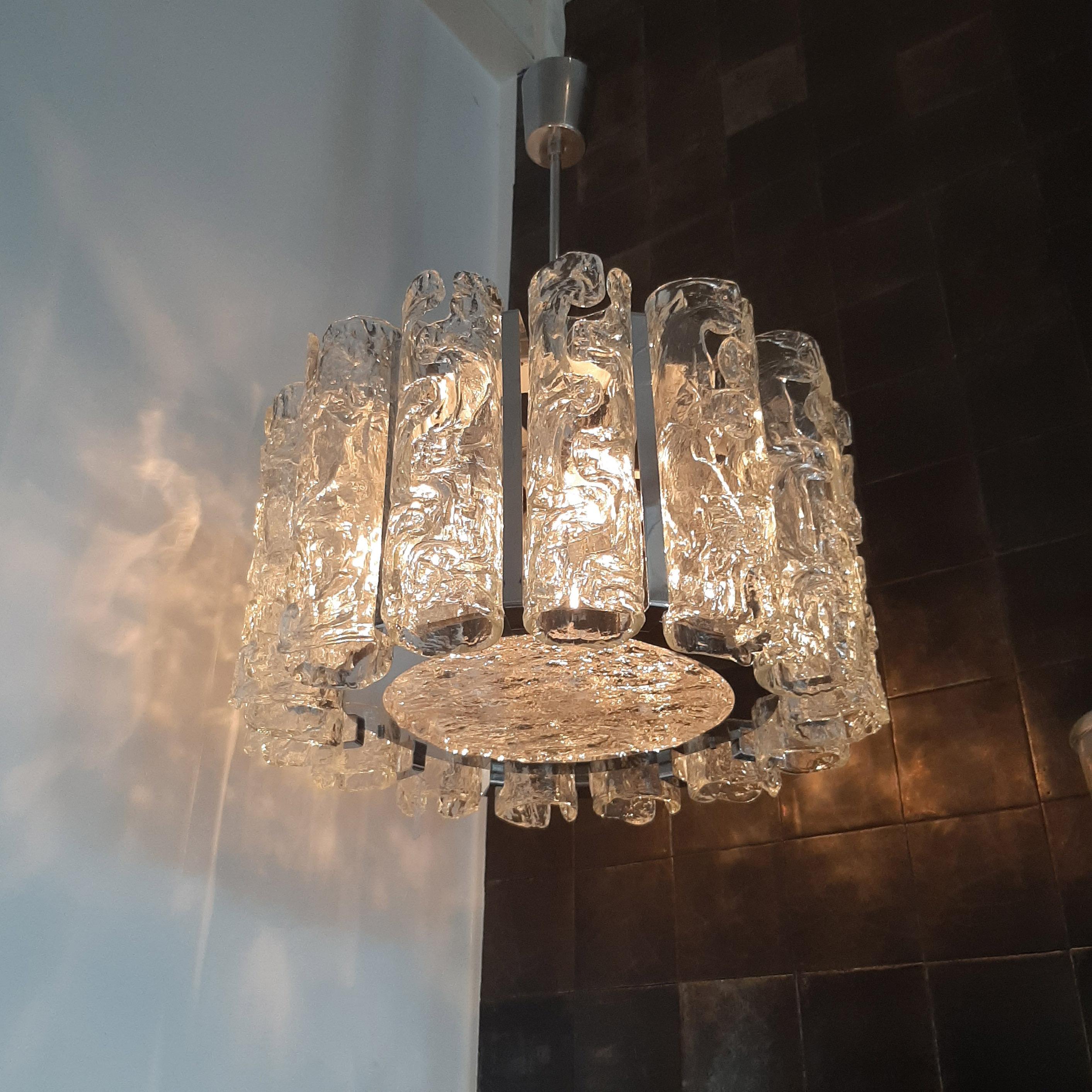 Vintage Italian glass and chrome Venini chandelier. The clear glass tubes have been worked with the Corteccia technique which gives them a bark-like texture effect and have been mounted on a chrome frame.
Venini designed luxury glass lighting. This