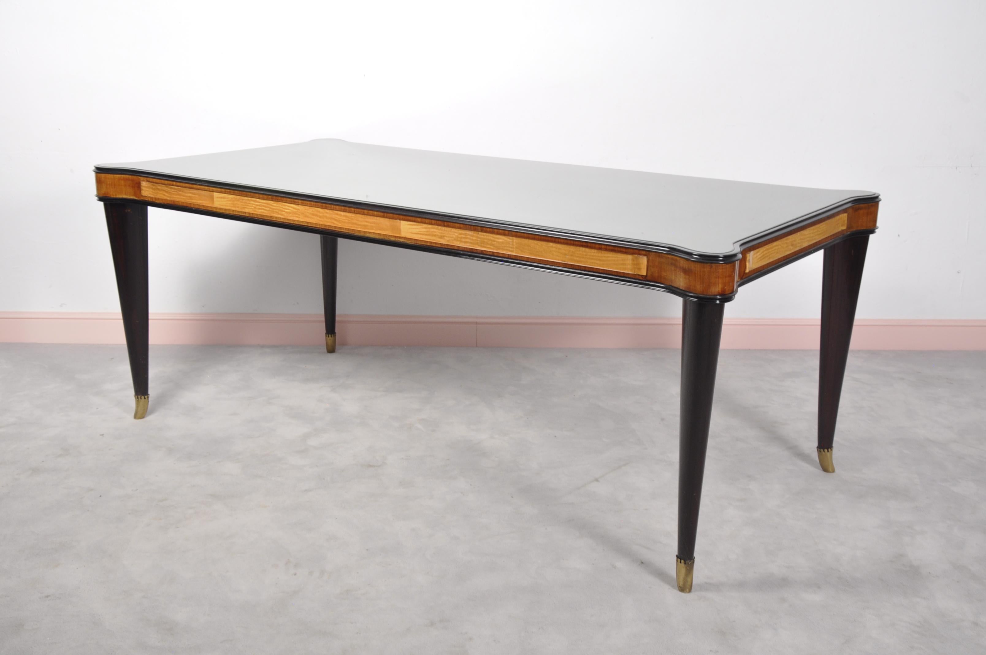 This dining table was designed by Paolo Buffa and features reverse painted gold glass plateau with original patinated brass sabots. The table also features round edges and a walnut base.

Mid-Century Modern Italian walnut dining table with brass