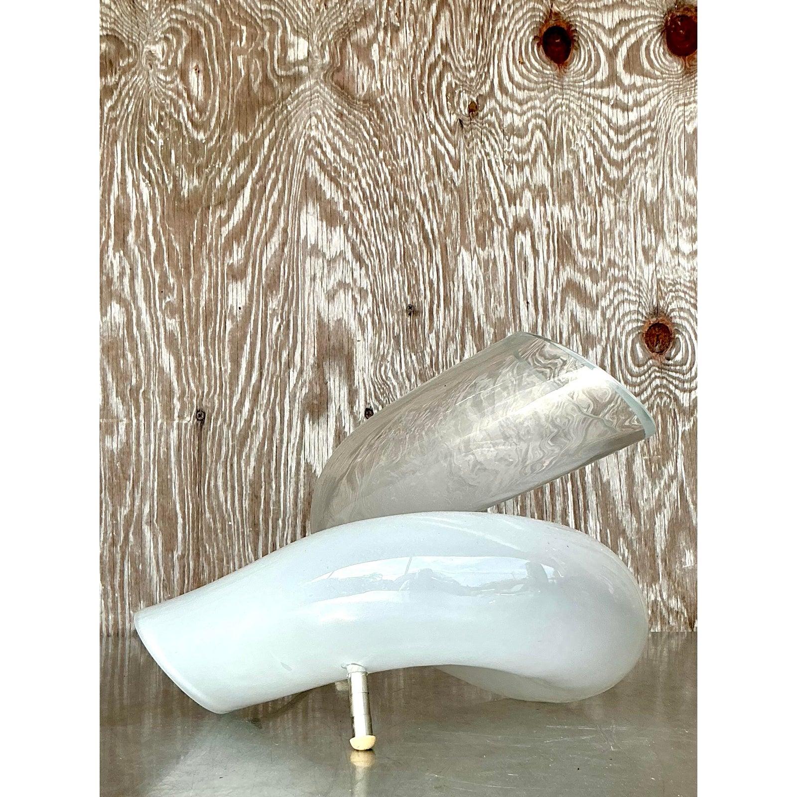 Cette superbe lampe de table en verre italien vintage est une véritable œuvre d'art, présentant une forme sculpturale exquise rappelant des rubans de lumière qui s'écoulent. Fabriquée avec un savoir-faire exceptionnel, la lampe présente des éléments