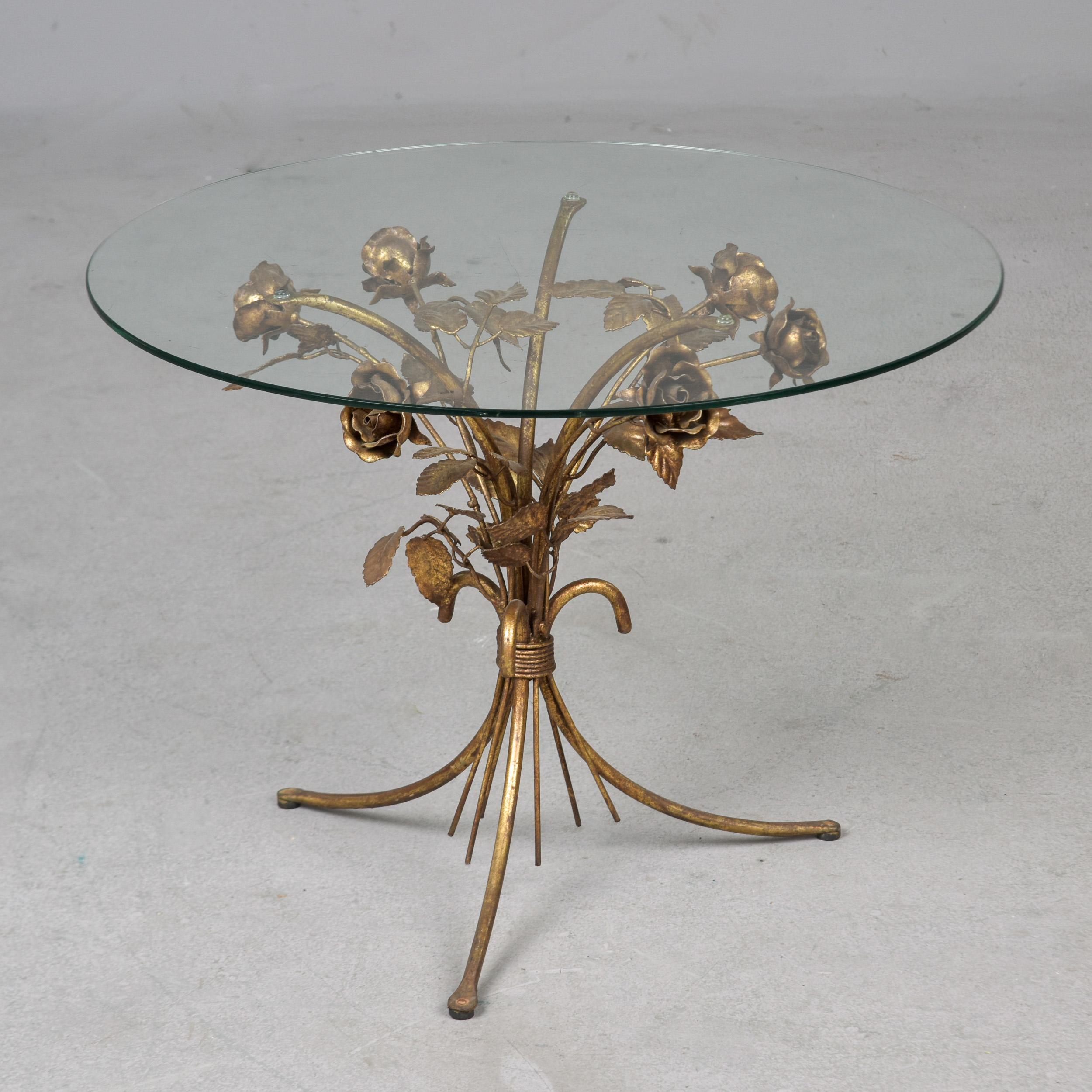 Trouvée en Italie, cette table d'appoint date des années 1950. La base est composée de pieds tripodes dorés avec des roses et des feuilles sculptées. Style classique Hollywood Regency ! Le plateau rond en verre transparent a un diamètre de 23,5