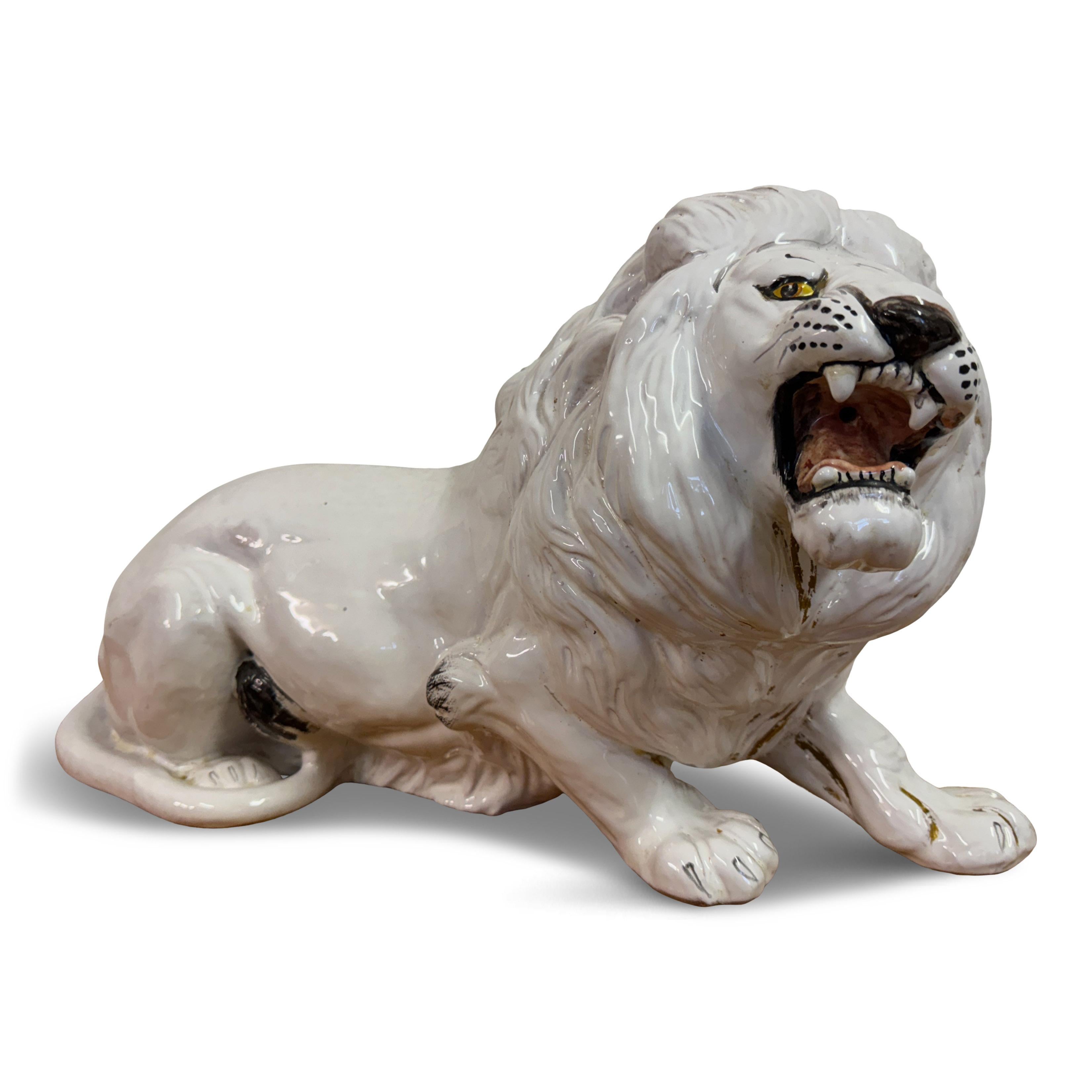 This striking ceramic sculpture depicts a majestic lion in a fierce, roaring pose. Crafted with meticulous attention to detail, the lion's body is elegantly sculpted to capture the powerful musculature and regal bearing of this king of the jungle.