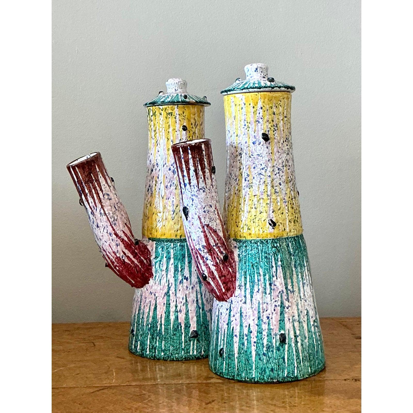 Infuse your space with the vibrant, artistic spirit of mid-century Italy with this captivating pair of vintage ceramic pitchers. Handcrafted with exceptional attention to detail, these vessels are a masterclass in form and color, showcasing a bold,