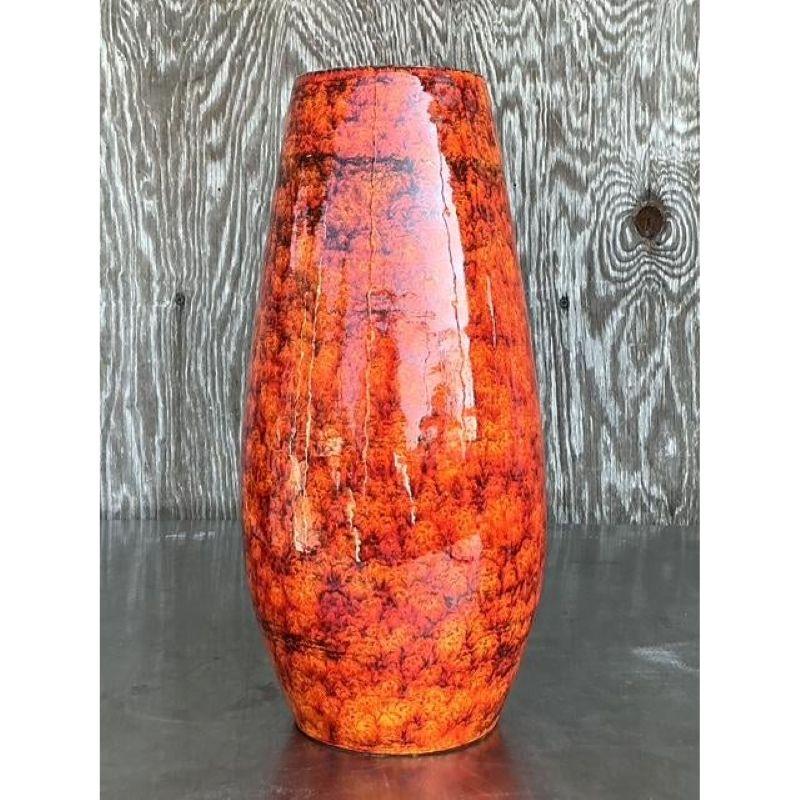 Questo splendido vaso vintage in ceramica italiana cattura lo spirito ardente dell'arte di metà secolo con la sua vibrante finitura a smalto lavico nei toni fusi del rosso, dell'arancione e del giallo. La superficie lucida danza con la consistenza e