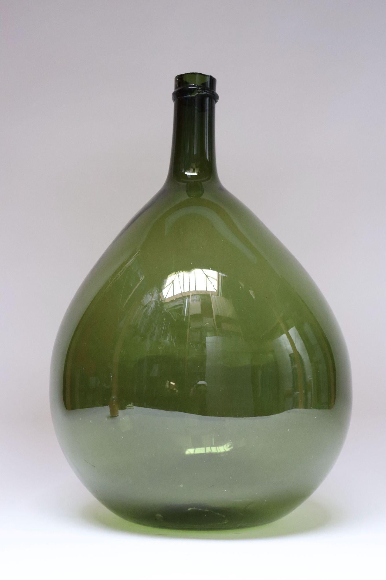 Italian Demijohn / Carboy originally used for transporting wine (ca. early 20th Century, Italy).
Composed of attractive green free-blown glass exhibiting trapped air bubbles within the glass itself with a slender, elongated neck with sheared lip and