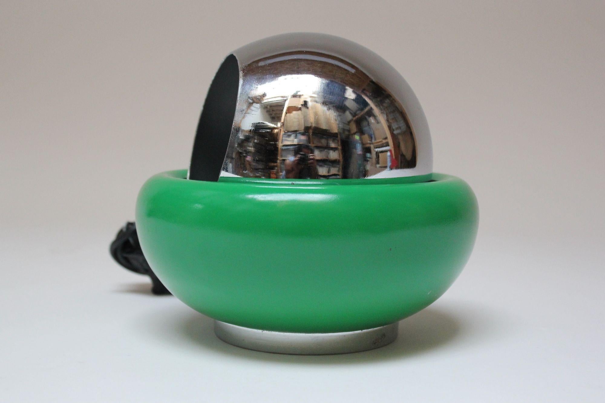 Table lamp designed by Goffredo Reggiani (ca. 1970s, Italy).
Composed of a chrome 'eye-ball' fixture housed within a magnetic green ceramic and chrome 'bowl' base. The magnetic function allows the fixture to maintain its stability after the position