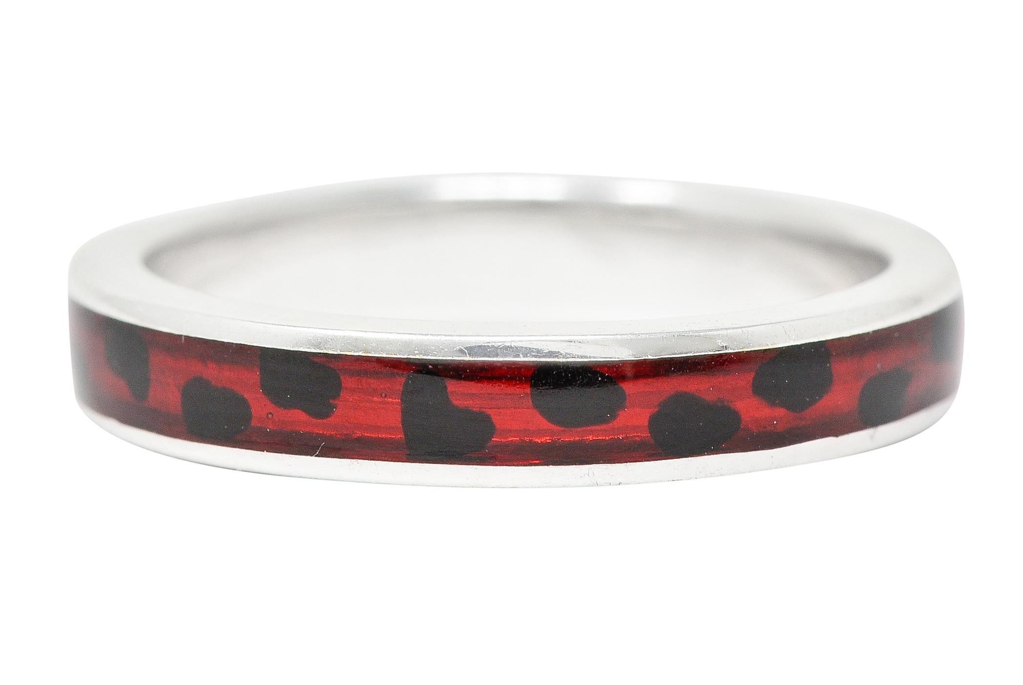 Band ring features a recessed guilloche enamel channel fully around. Transparent medium red in color - glossed over engraved linear pattern. With opaque black enamel cheetah style spots. Accented by high polished gold surround. Stamped 18kt for 18