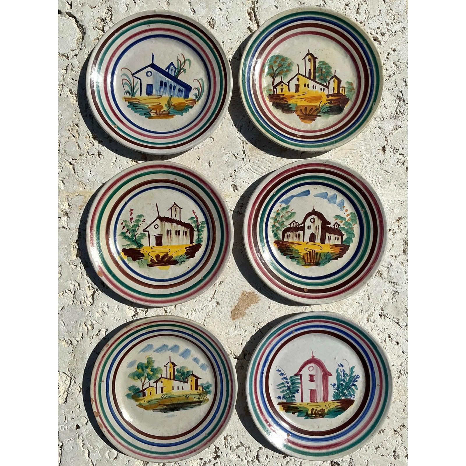 Capture the charm of rustic Italian countryside living with this exquisite set of six vintage hand-painted ceramic dishes. Each plate features a unique pastoral scene—quaint churches, cottages, and vibrant flora—brought to life with colorful
