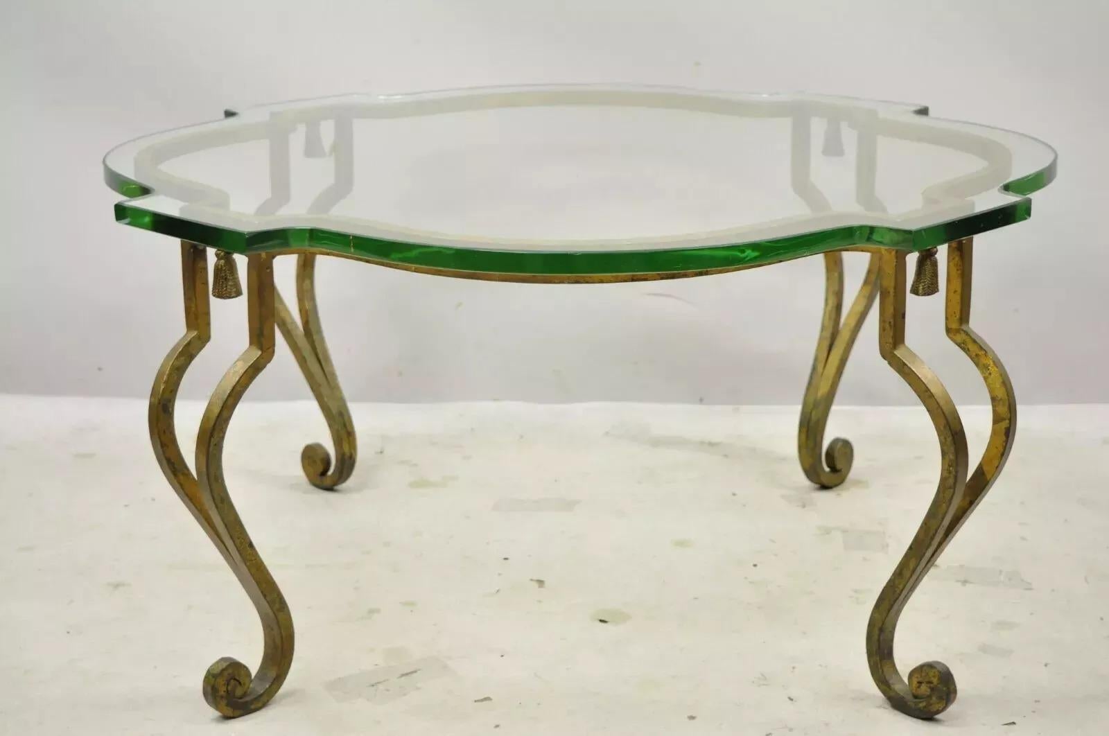 Italian Hollywood Regency Distressed Gold Gilt Iron Scalloped Glass Coffee Table. Item features a heavy iron scrollwork base with tassels, thick scalloped shaped glass top, distressed gold finish, cabriole legs, great style and form. Circa Mid 20th