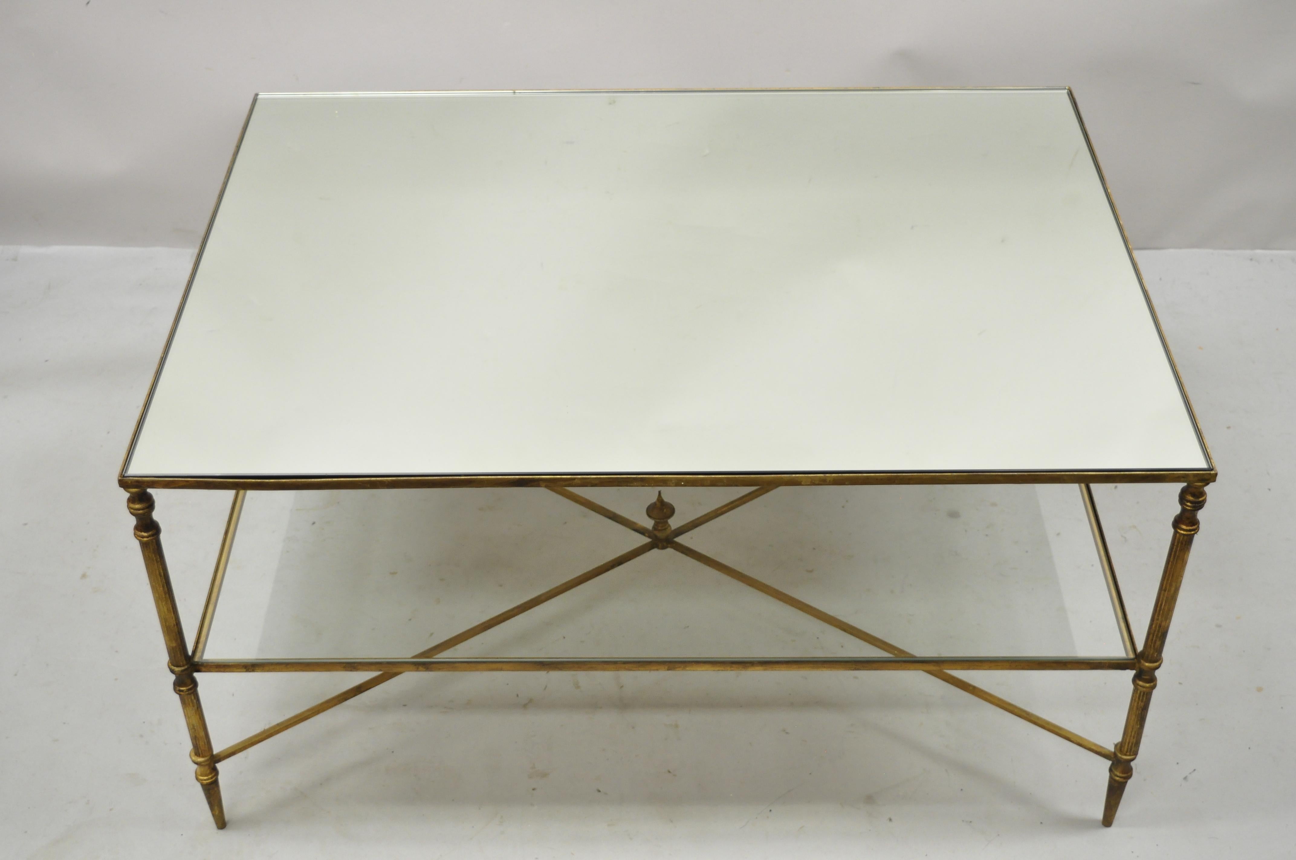 Vintage Italian Hollywood Regency gold iron frame coffee table with mirror top. Item features mirror glass top, clear glass lower shelf, iron frame, gold distressed finish, cross stretcher base, very nice vintage item, great style and form. Circa