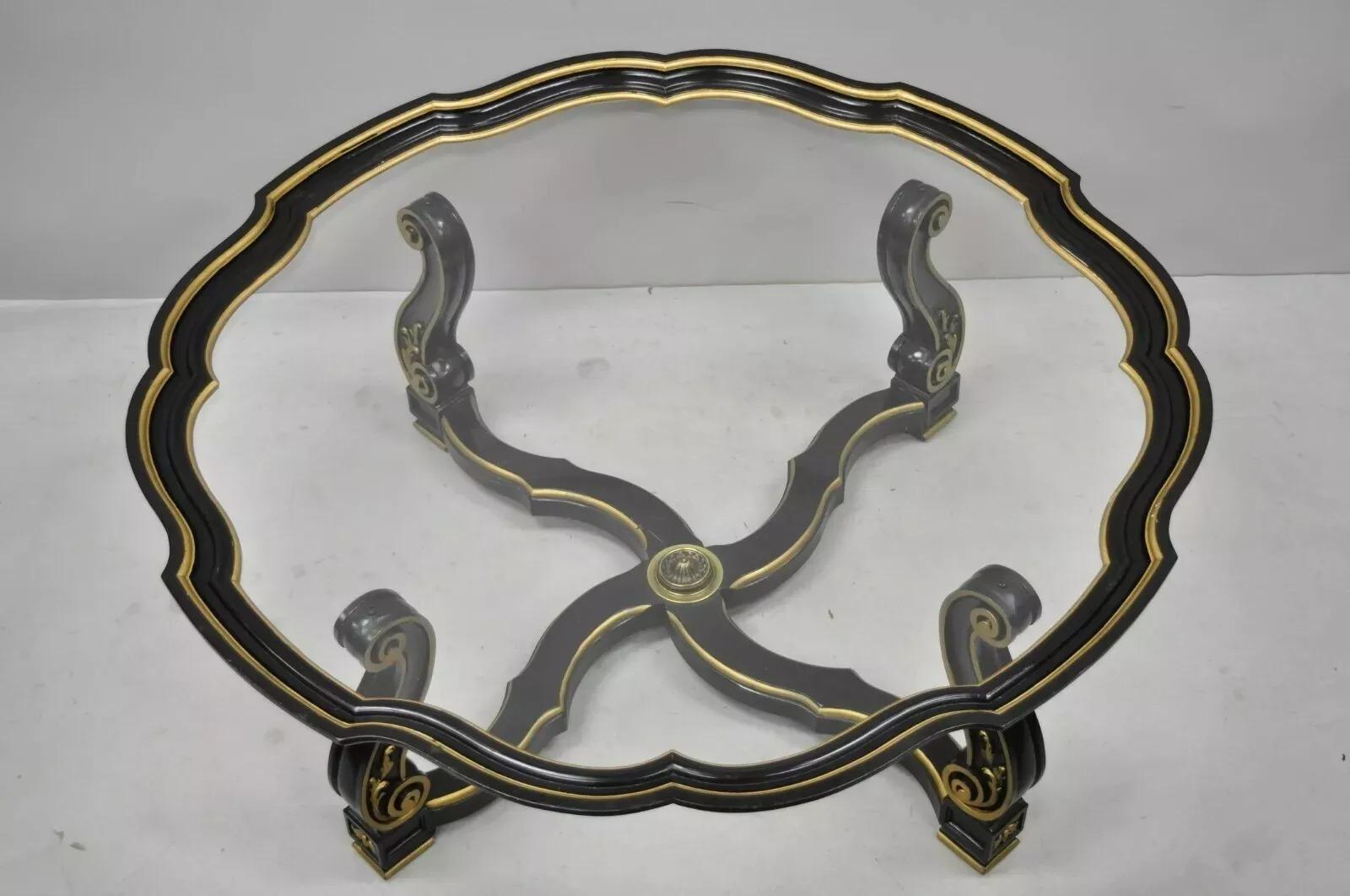 Table basse vintage italienne à plateau en verre noir et or, style Hollywood Regency, avec bord festonné. Cet article présente une finition peinte en noir et or, une base sculptée, un plateau en verre, une bordure façonnée, un épi de faîtage en