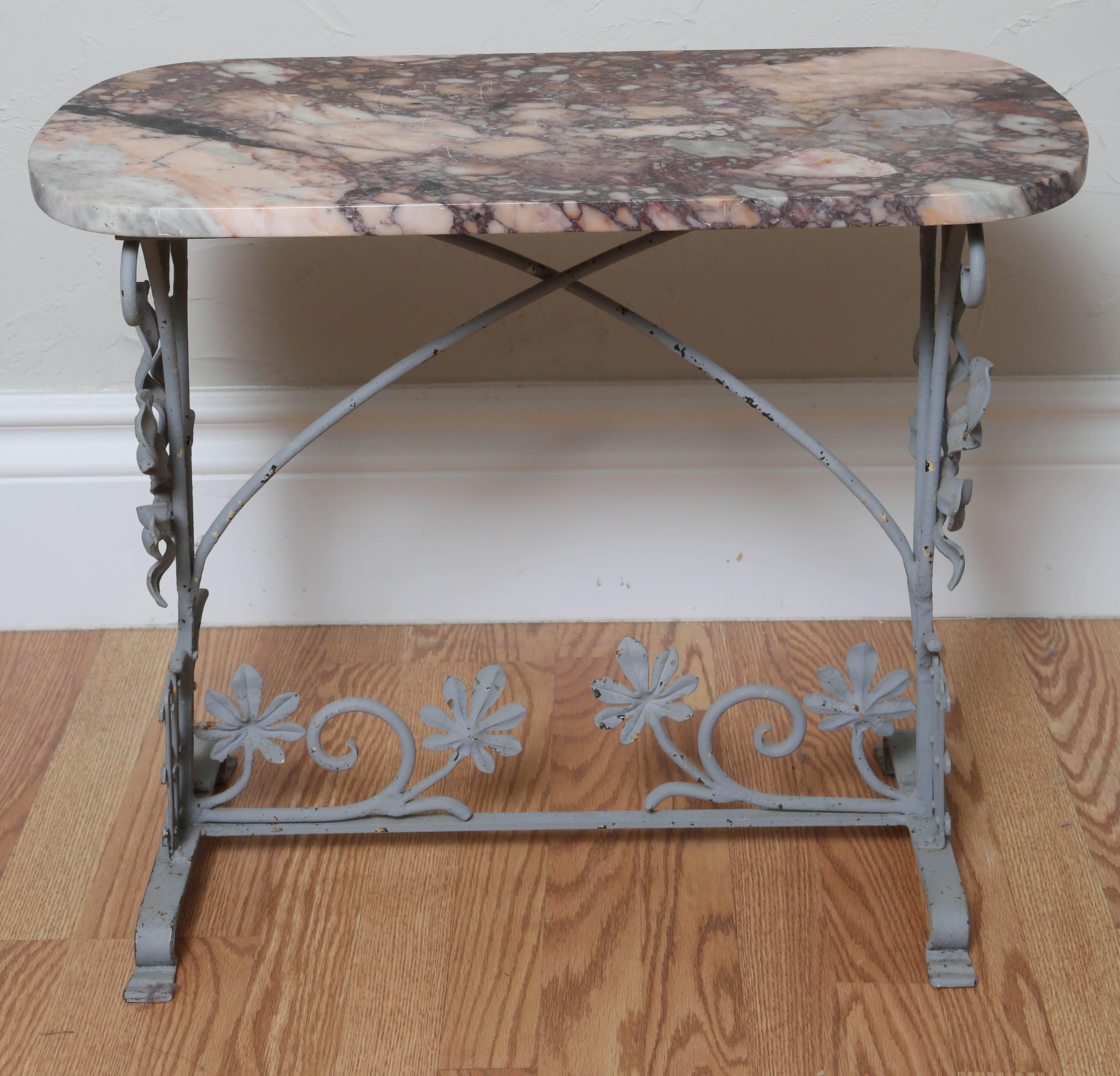 Wrought iron basket motif side table with pink/grey colored marble top.