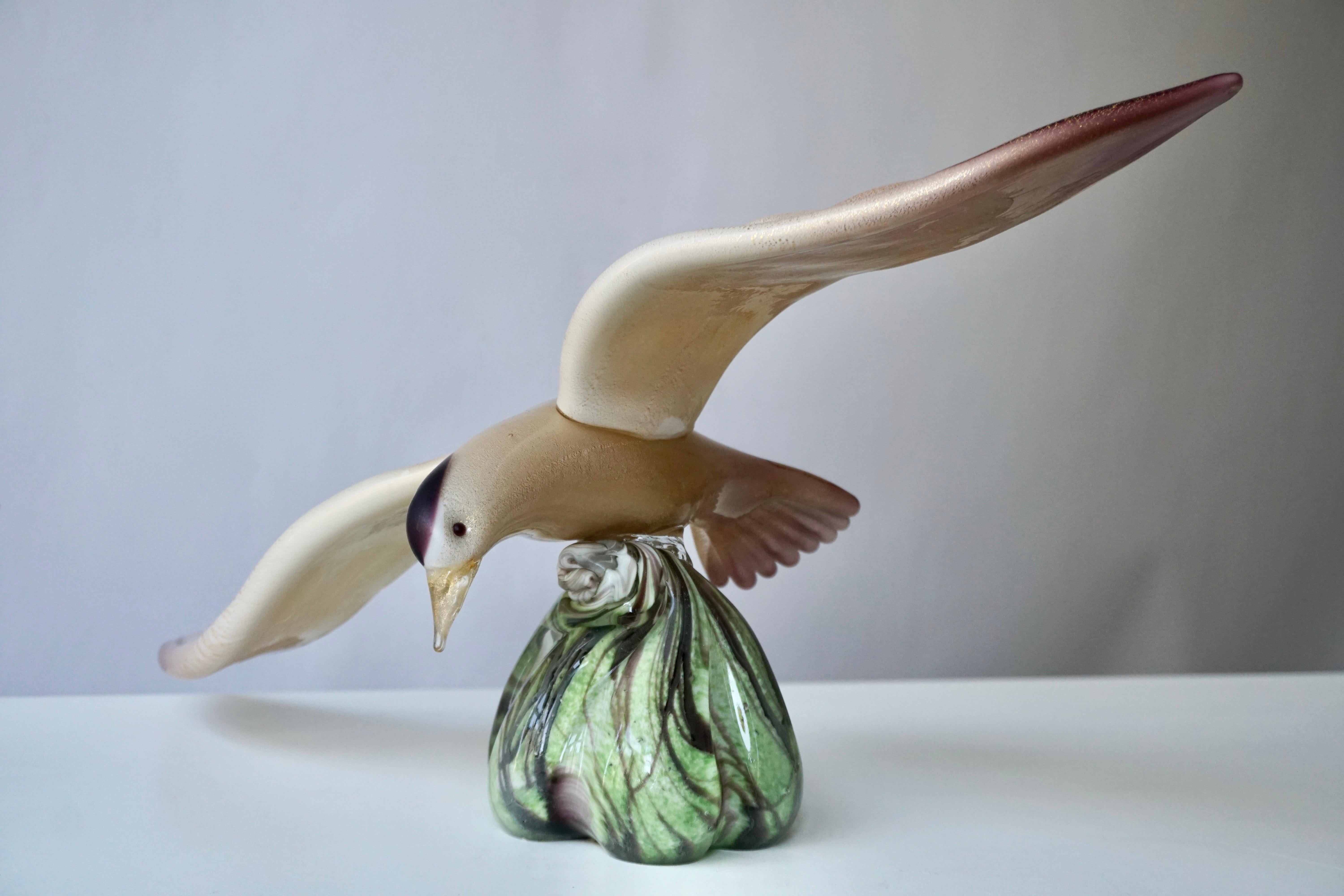 Diese ausdrucksstarke fliegende Vogelskulptur aus Glas aus den 1970er Jahren ist ein wahres Kunstwerk aus mundgeblasenem Muranoglas mit einem Dekor in Lila, Creme, Gold und Grün.

Maße: Breite 45 cm.
Gewicht 3 kg.