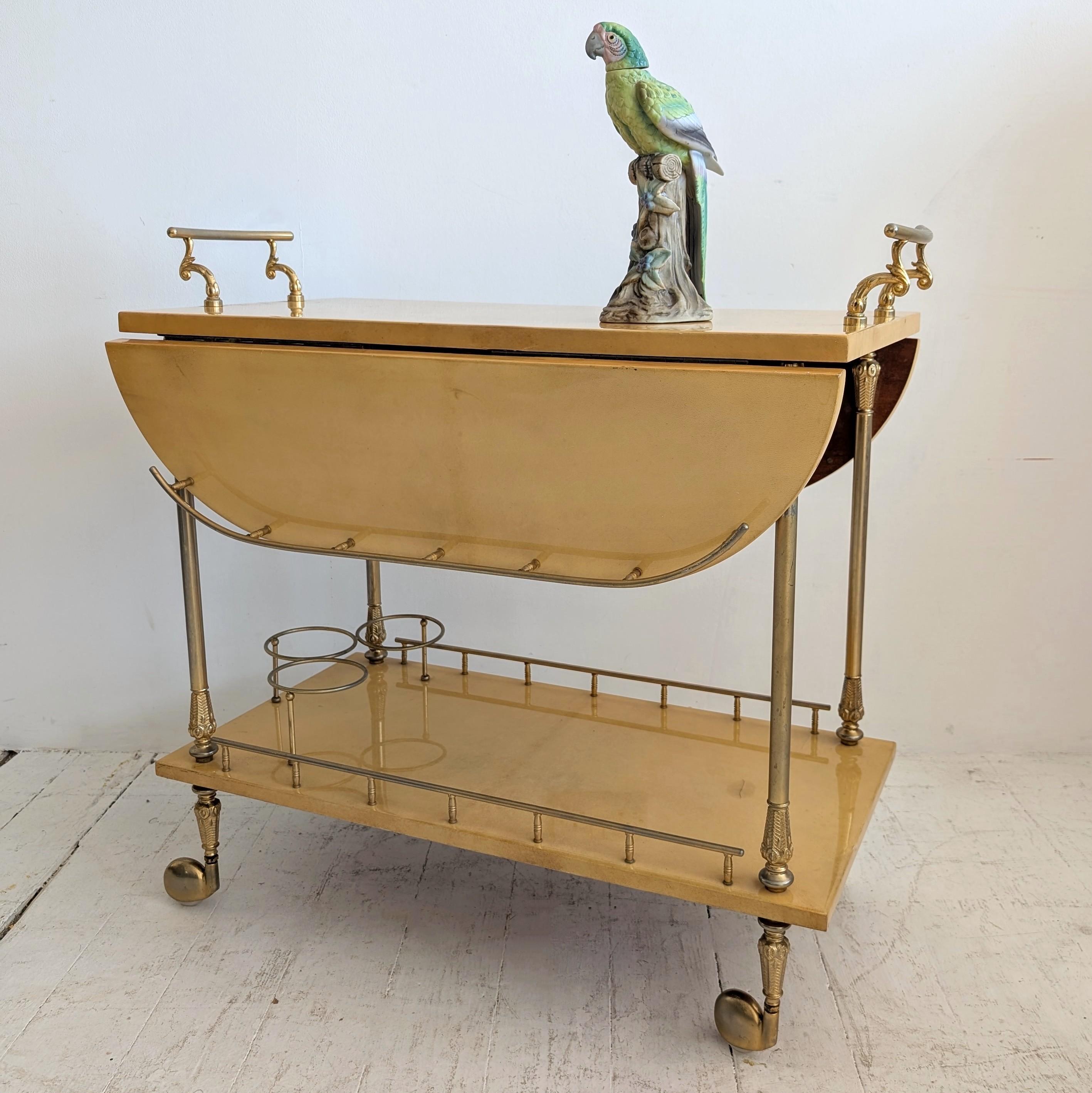Rare chariot à boissons à deux niveaux en parchemin laqué italien par Aldo Tura, Italie années 1960.

Le niveau supérieur de cette table roulante est doté de deux côtés à rabat et d'une carafe ou d'un porte-bouteille en métal doré sur le niveau