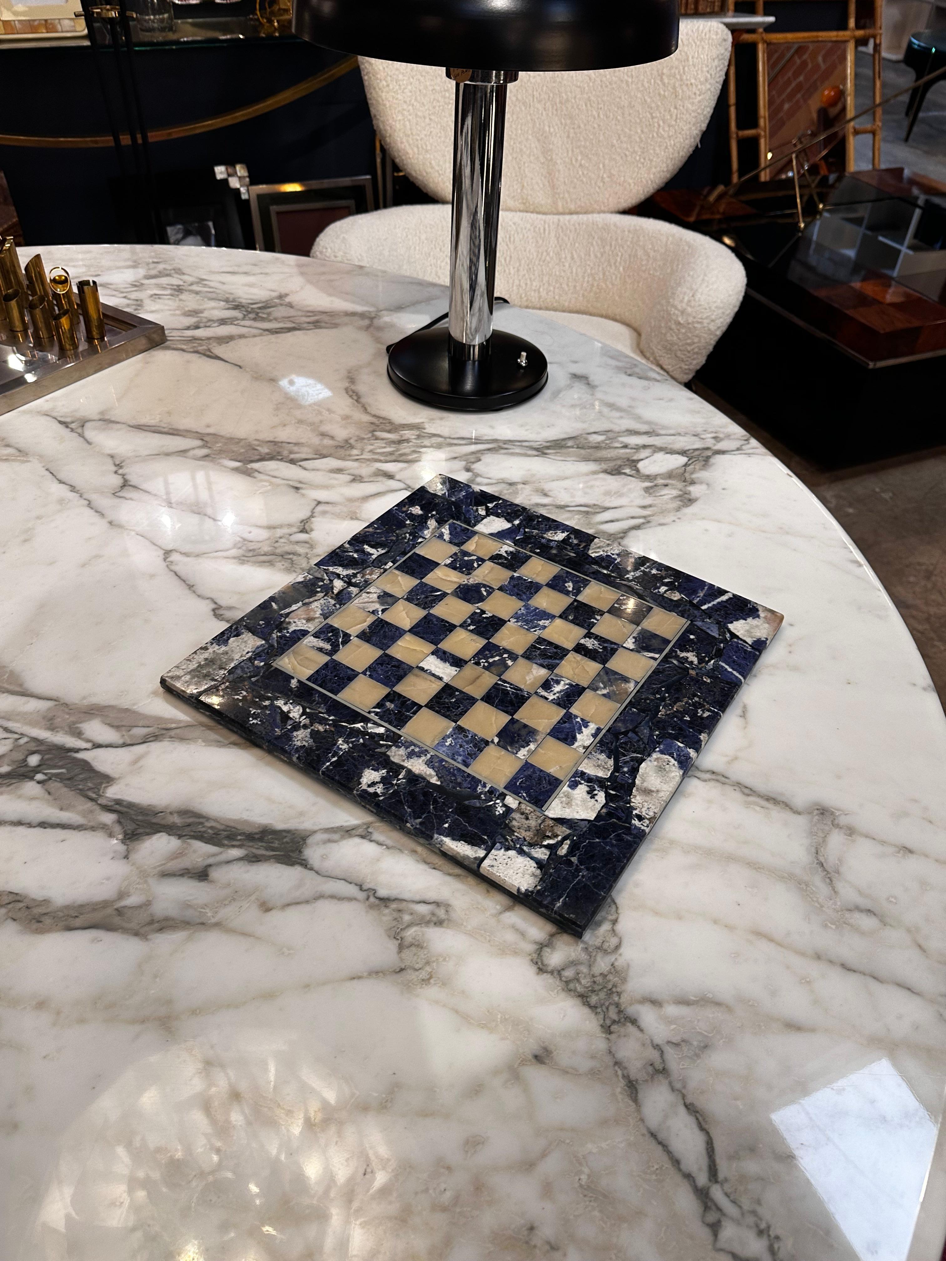 Embark on a journey of opulence with our Vintage Italian Lapis Lazuli Chess Board, a striking piece from the 1980s. This exquisite chess board, meticulously crafted in Italy, showcases the timeless beauty of lapiz lazuli. The deep blue hues and
