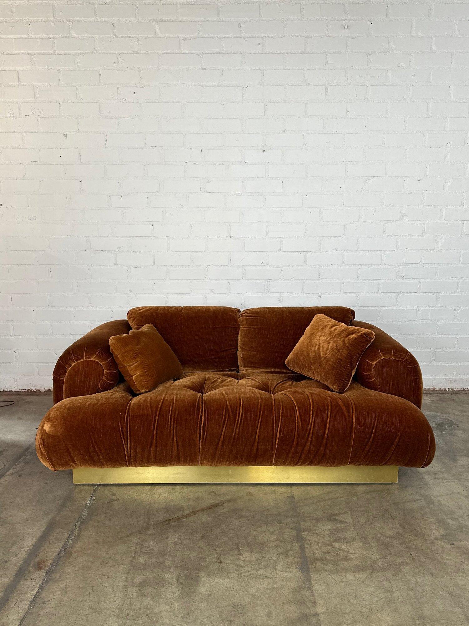 W70 D40 H29 SW60 SD27 SH15

Vintage velvet and brass overstuffed sofa on a plinth base. Plinth is brass covered on all sides except the backside. Original fabric is in great condition with no major areas of damage and no visible rips. Sofa is