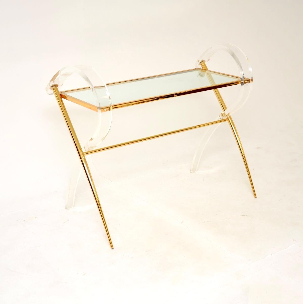A stunning vintage Italian Lucite and gold finish console table, dating from the 1970’s.

It has a very decorative style and is of lovely quality. The frame is made from clear acrylic and gold finished aluminium, the table surface is inset removable