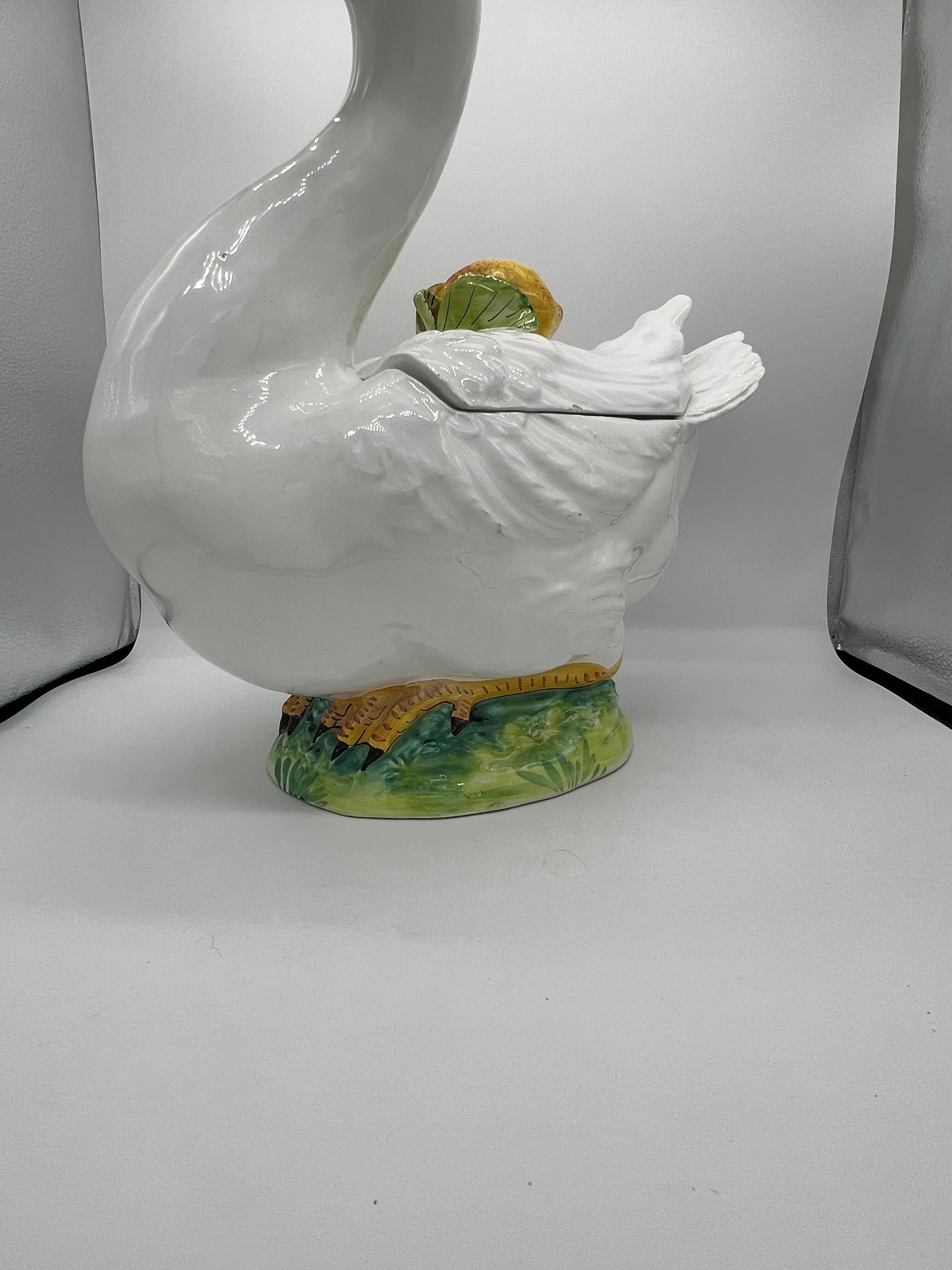 A vintage Italian ceramic goose tureen. The goose features a realistic appearance with colored beak and eyes. The back feathers are mounted with a lemon motif finial and lifts off to reveal the central open body tureen. Marked to underside Made In