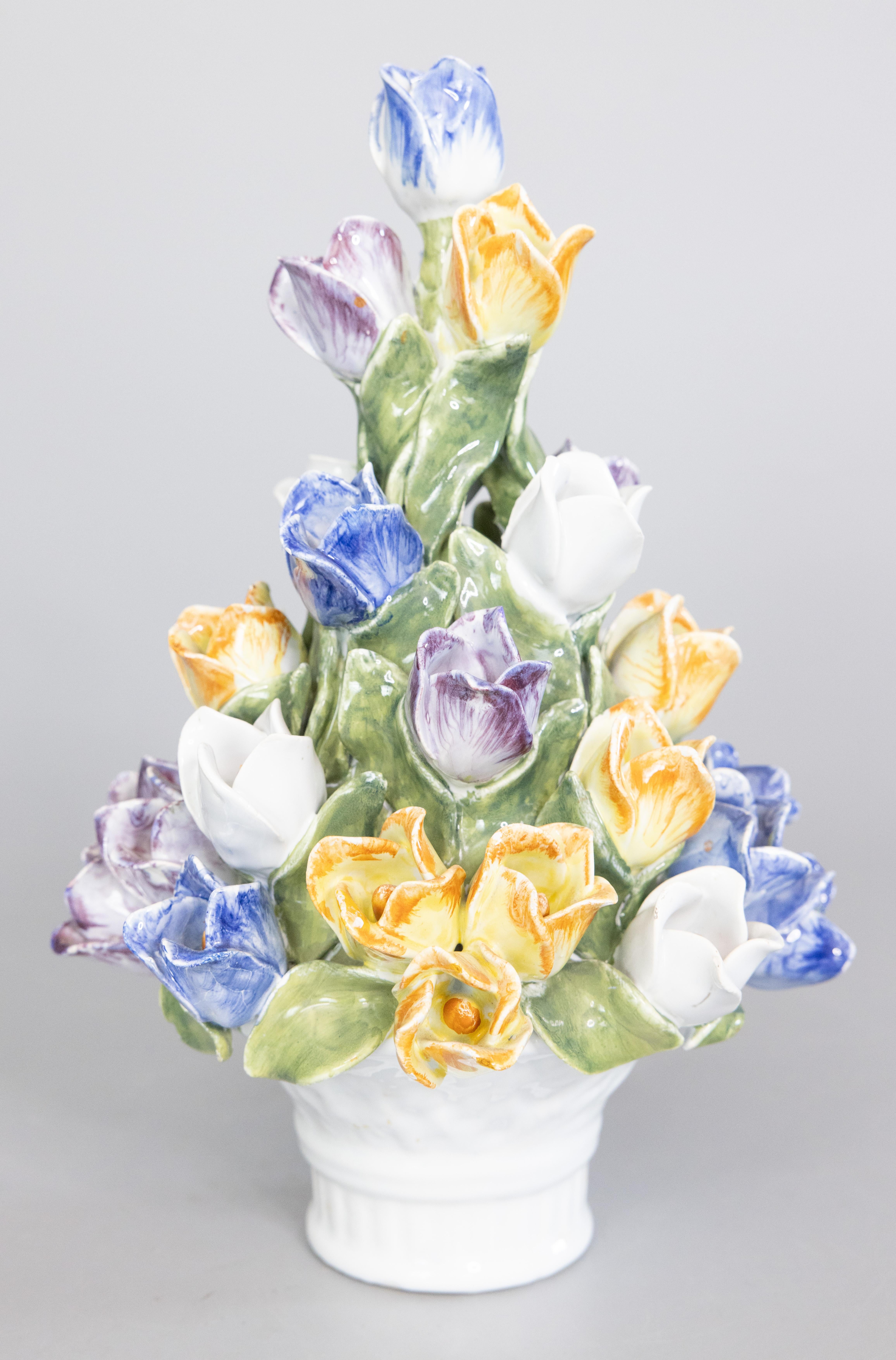 A beautiful vintage ceramic Italian topiary centerpiece, adorned with yellow, blue, lavender, and white tulips in a white lattice work basket. Made by the Bassano Zortea studio in northern Italy, circa 1950.