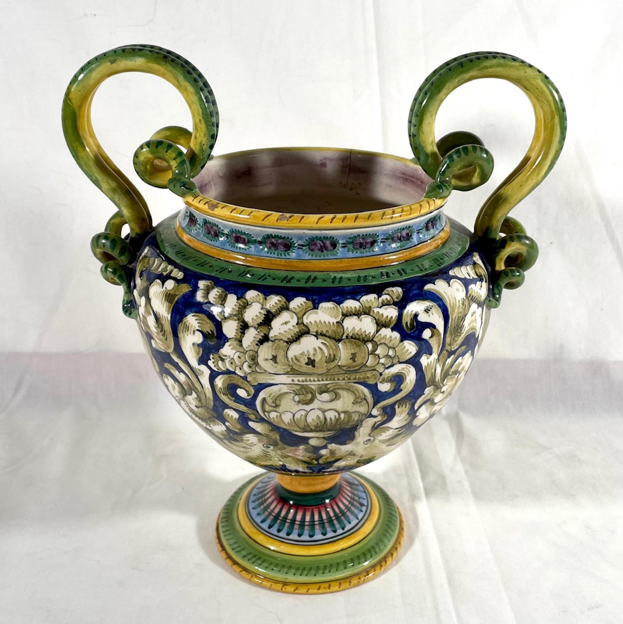Vintage Italian Majolica two-handled urn

Charming vintage Italian Majolica two handled urn. This lovely vintage bulbous urn is hand decorated with acanthus leaves and overflowing fruited urns against a rich dark blue background. Two extended
