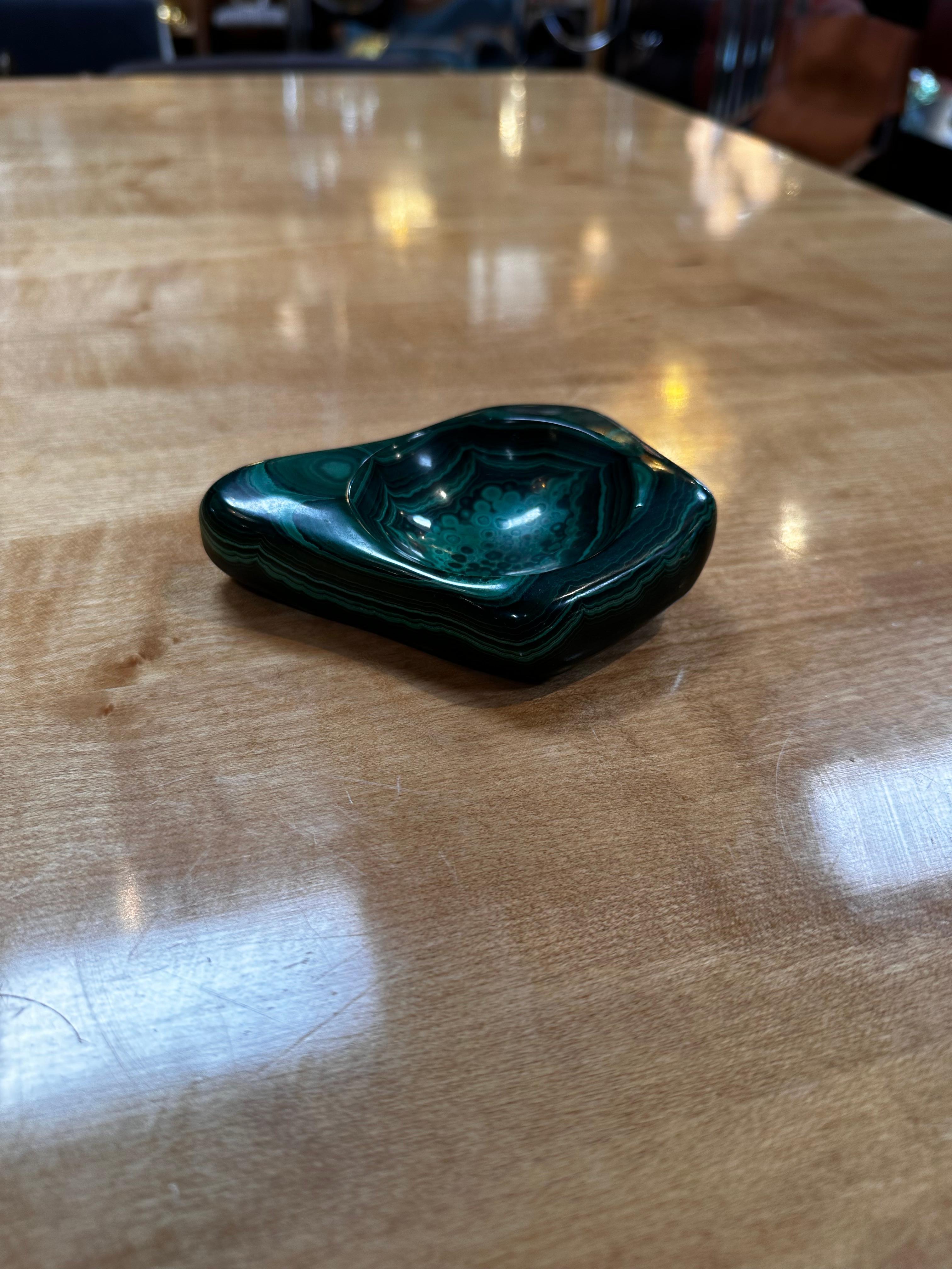 The Vintage Italian Malachite Ashtray from the 1960s is a unique and eye-catching piece of decorative art. Crafted in Italy during the mid-20th century, the ashtray is made from malachite, a vibrant green mineral known for its distinctive color and