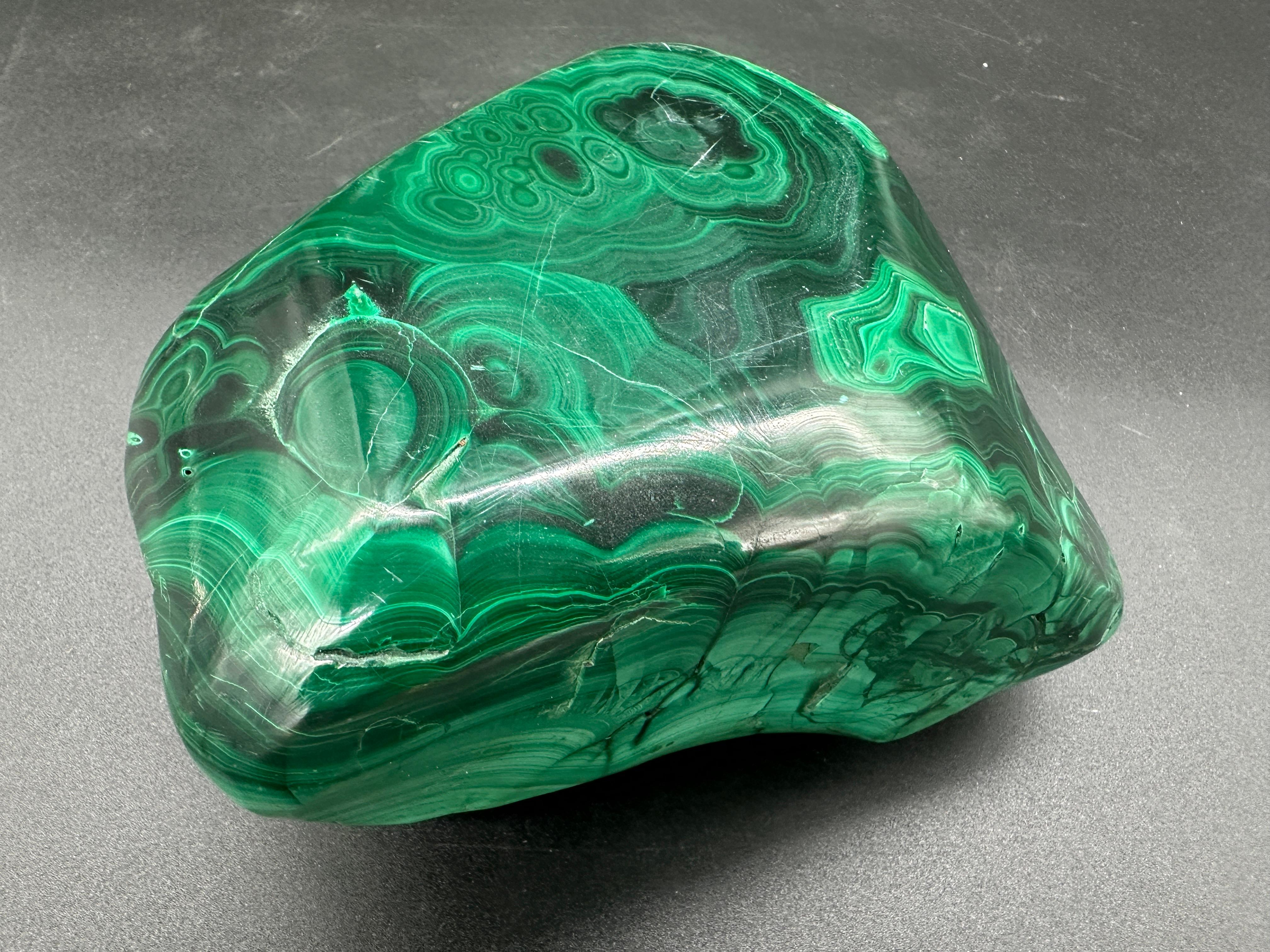  Uno splendido posacenere in malachite degli anni '80, che mette in mostra la bellezza naturale di questo vibrante minerale verde. Realizzato con grande maestria in Italia, il posacenere è caratterizzato da motivi intricati e da una finitura liscia