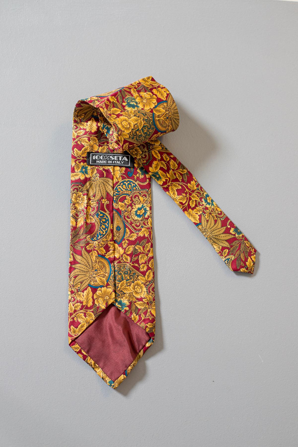 Multicolore, excentrique et élégante, cette cravate est de fabrication italienne, elle est composée de 100% de soie. Véritable evergreen, cette cravate est intemporelle, ornée de motifs cachemire dorés avec quelques détails bleus sur un fond rouge.