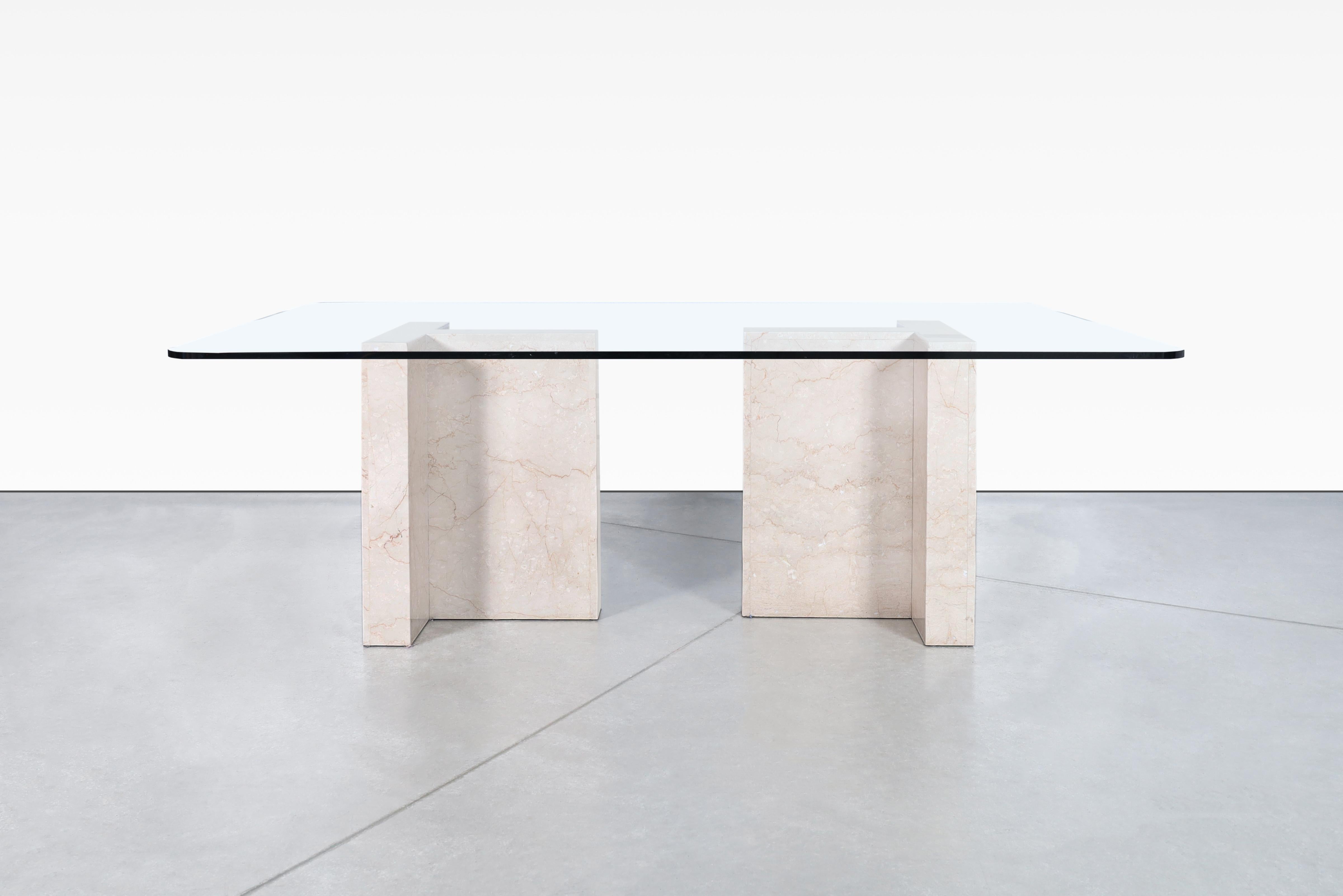 This beautiful Italian marble dining table from the 1980s boasts a unique and elegant design. The table features two sturdy marble bases, which are shaped like a T and showcase intricate veins that add to the table's charm and character. The thick