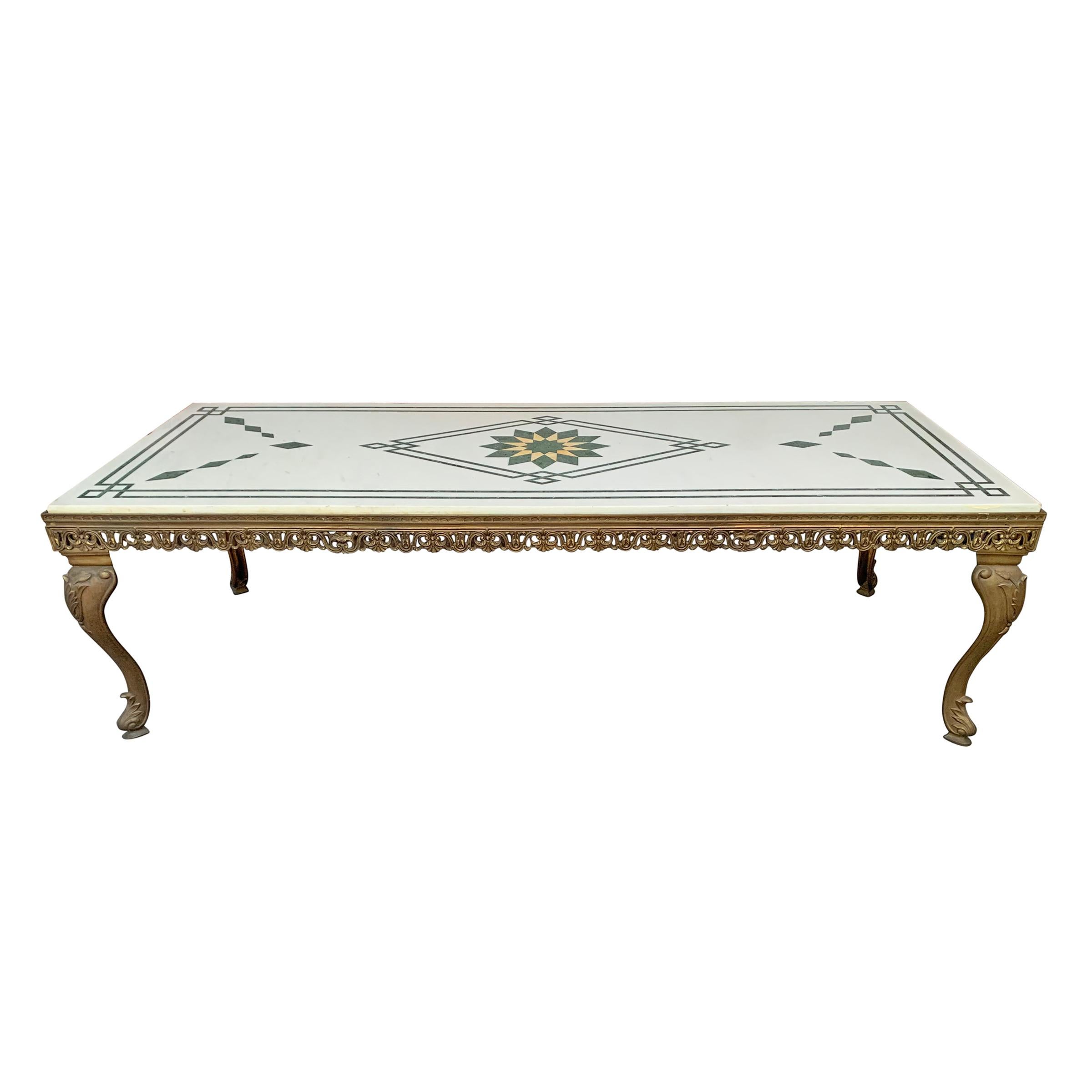A wonderful vintage Italian low table with a white marble top with a green marble inlaid pattern of geometric design including a green and yellow starburst in the center surrounded by a stylized Greek key border. The base is cast bronze with
