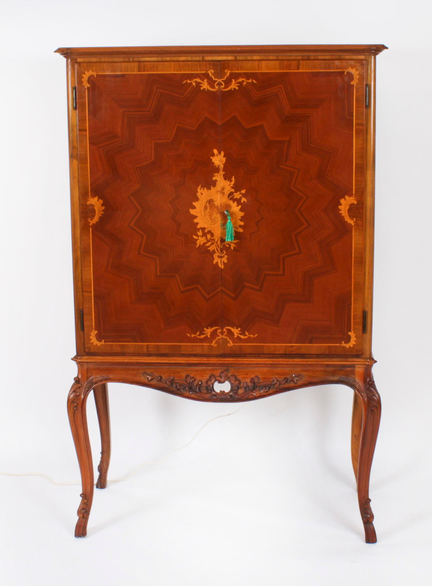 This is a stupendous vintage Italian Mid Century marquetry inlaid burr walnut drinks cabinet, Circa 1950 in date.

The pair of doors with central satinwood floral cartouche inlay and extending star pattern parquetry open to reveal a stunning maple