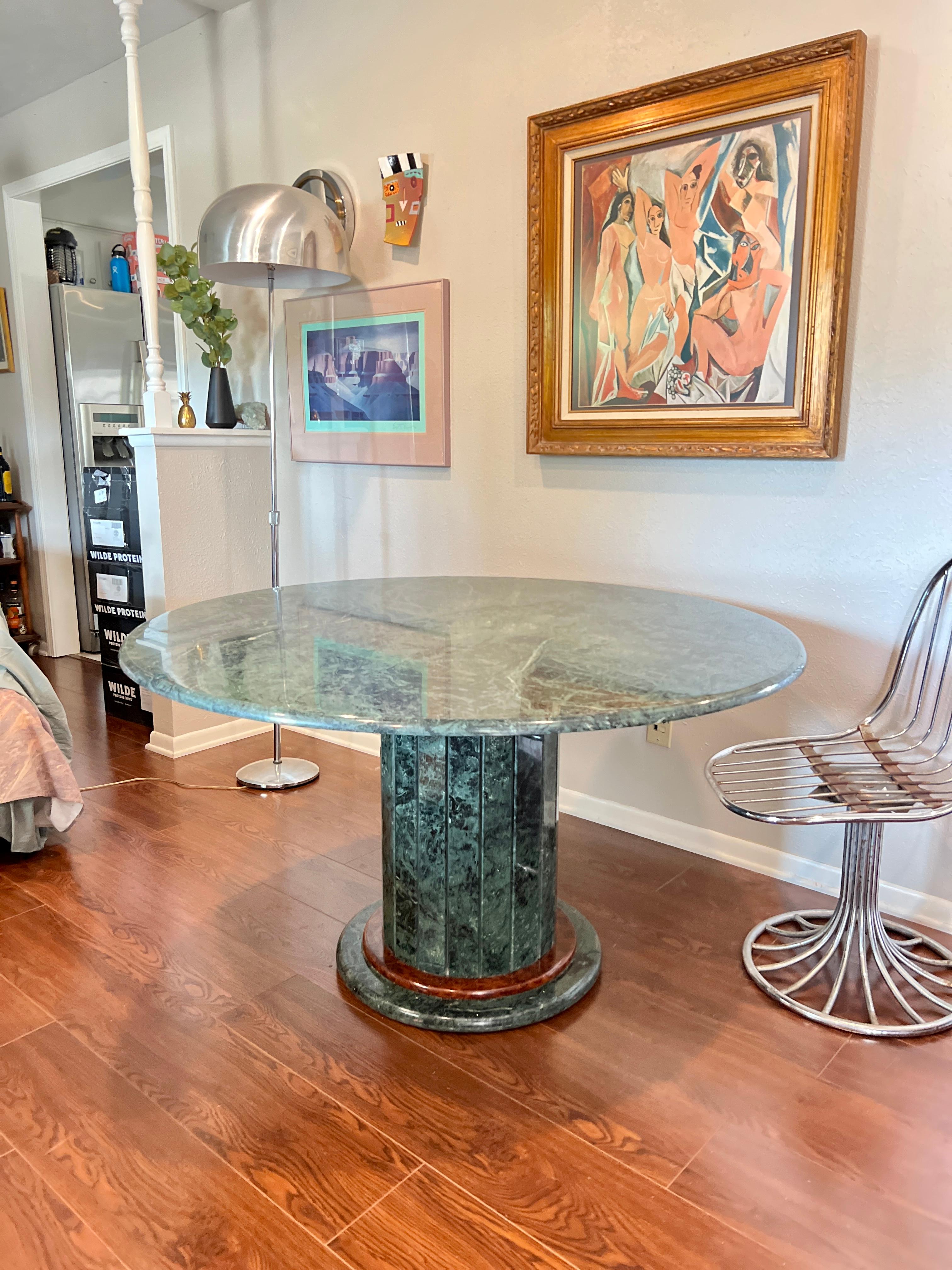 Amazing vintage circular dining table in green marble with a beautiful paneled base. In very good condition without any damages, cracks or repairs. There are some minor flaws/scratches on the surface and there are remnants of material removal on the