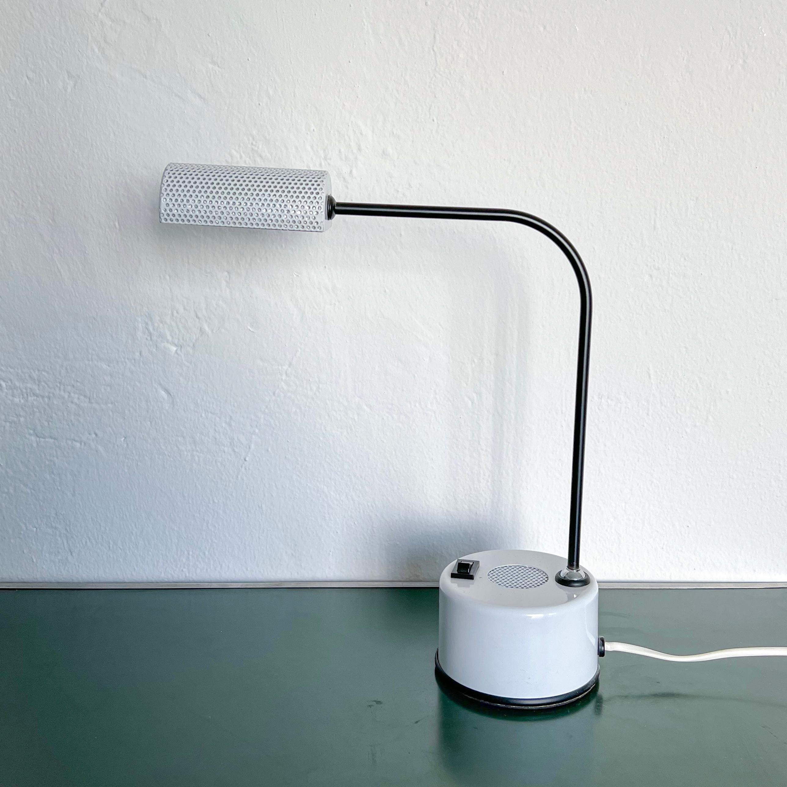 This is a cool little desk lamp, dating back to the early Eighties and crafted in white and black metal. The main arm can be tilted and oriented, and the lampshade can be rotated, thus directing light in the preferred direction.

Some details,
