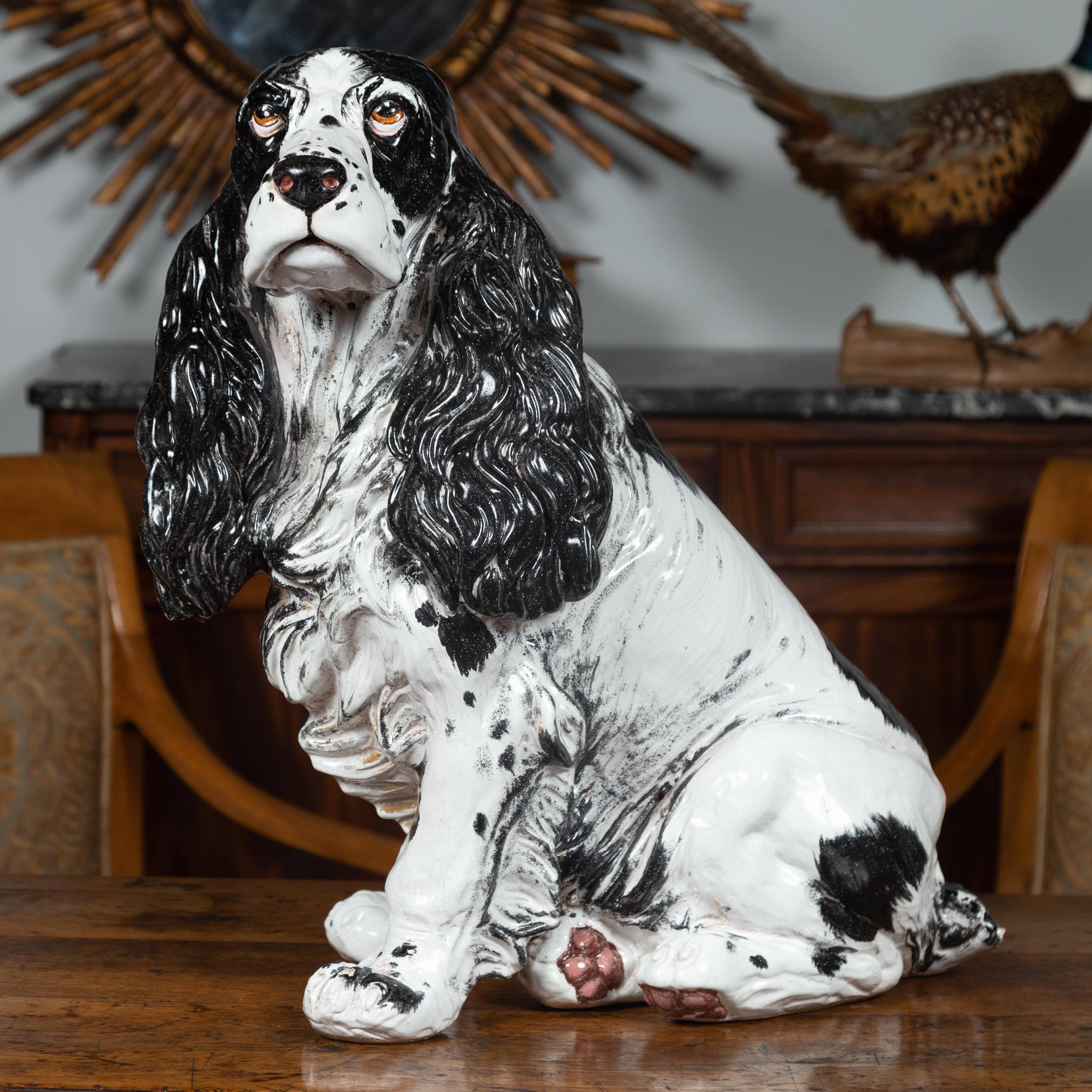 An Italian vintage black and white terracotta spaniel dog sculpture from the mid-20th century. We are immediately drawn to the sweetness of this Italian terracotta sculpture depicting a black and white spaniel dog, sitting gracefully on his behind,