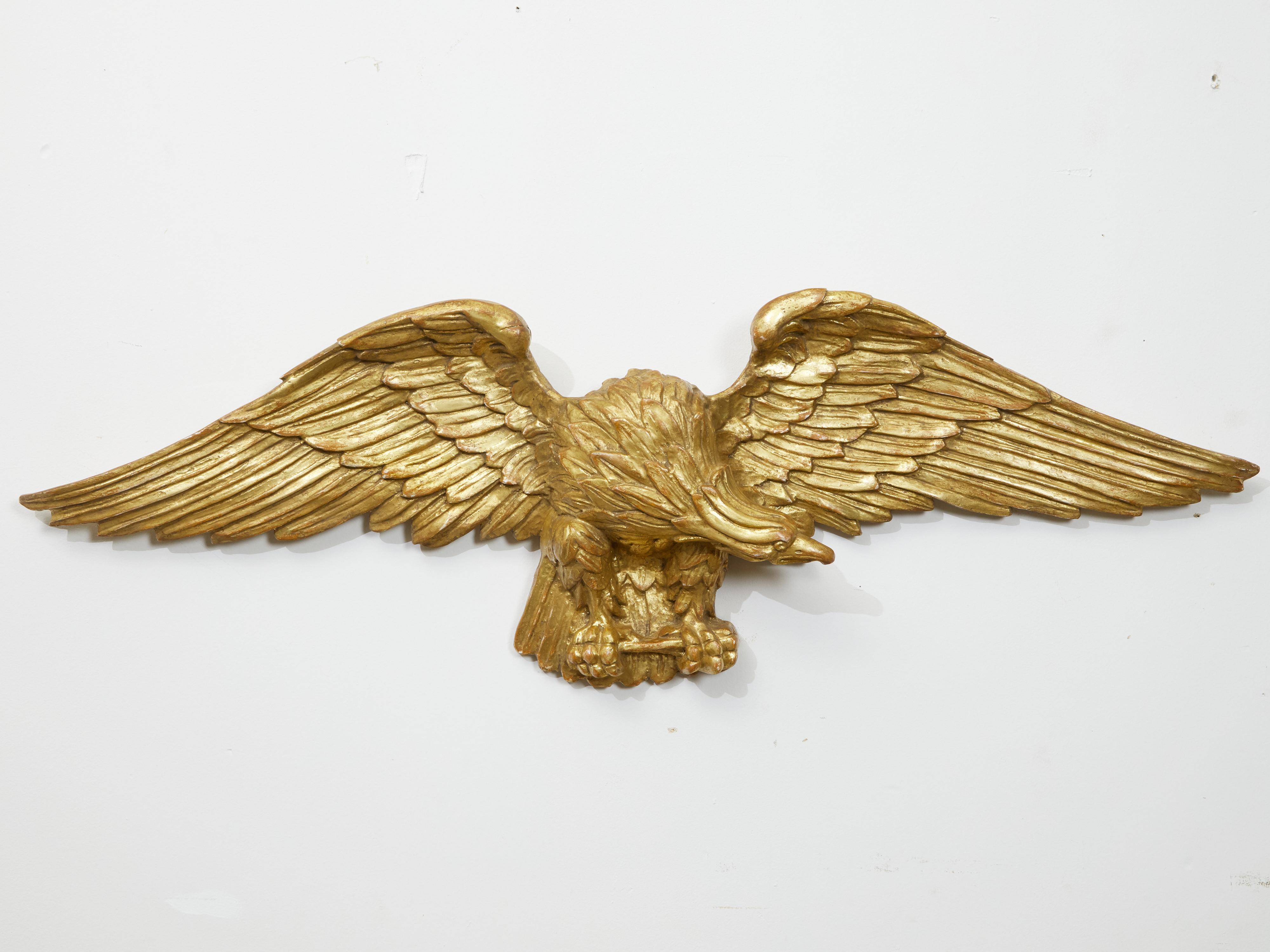 A vintage Italian carved giltwood eagle from the mid 20th century, with extended wings. Created in Italy during the midcentury period, this carved sculpture features a majestic eagle, his wings fully extended, his talons firmly grasping the branch