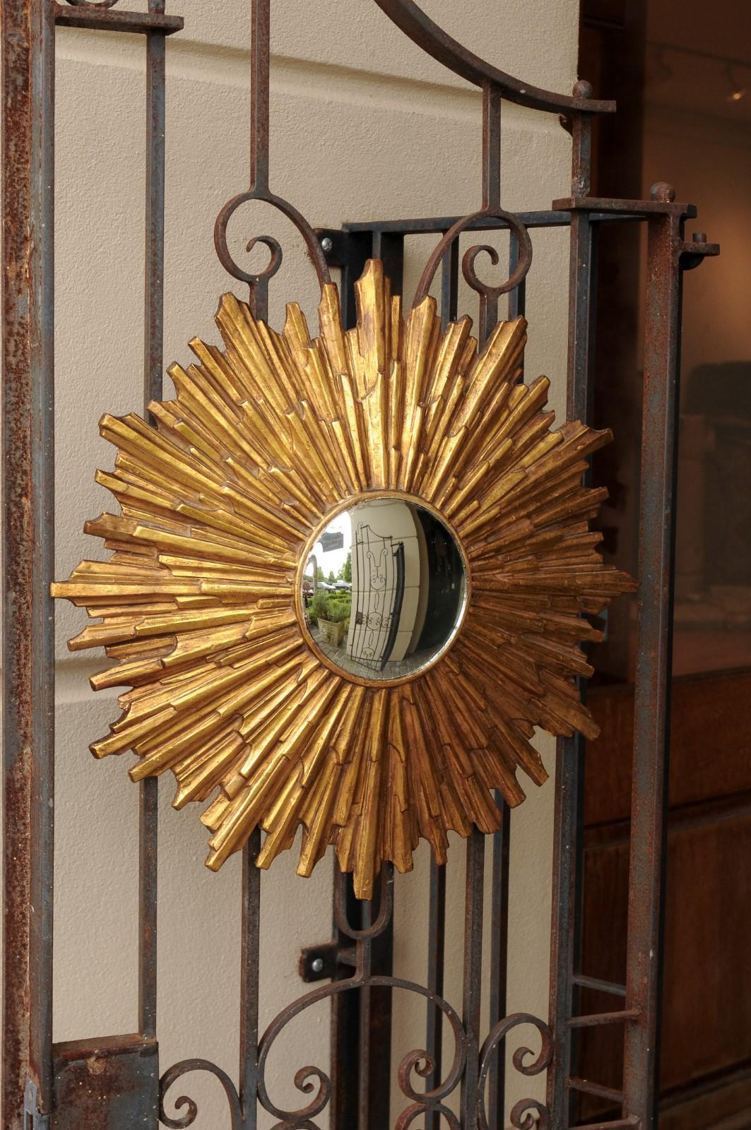 A vintage Italian gilt composition sunburst mirror from the mid-20th century with rays of varying sizes and convex mirror. Born in the third quarter of the 20th century, this Italian sunburst mirror features a central convex mirror that distorts