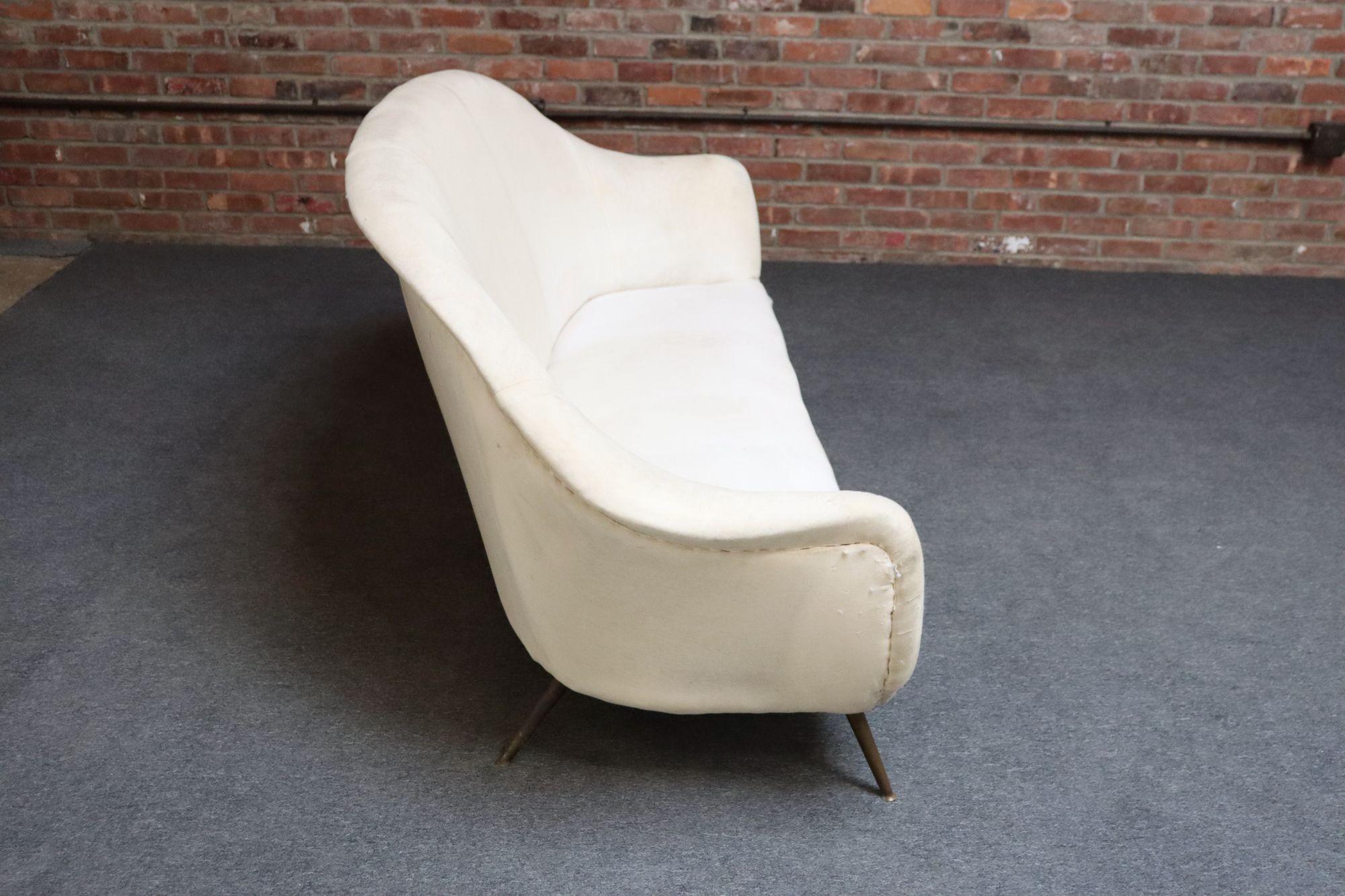 Canapé italien vintage de forme organique avec des accoudoirs sculpturaux en forme d'ailes et un dossier profondément incurvé soutenu par quatre pieds en laiton évasés (vers les années 1950).
Design/One chic et moderniste, se présentant bien sous