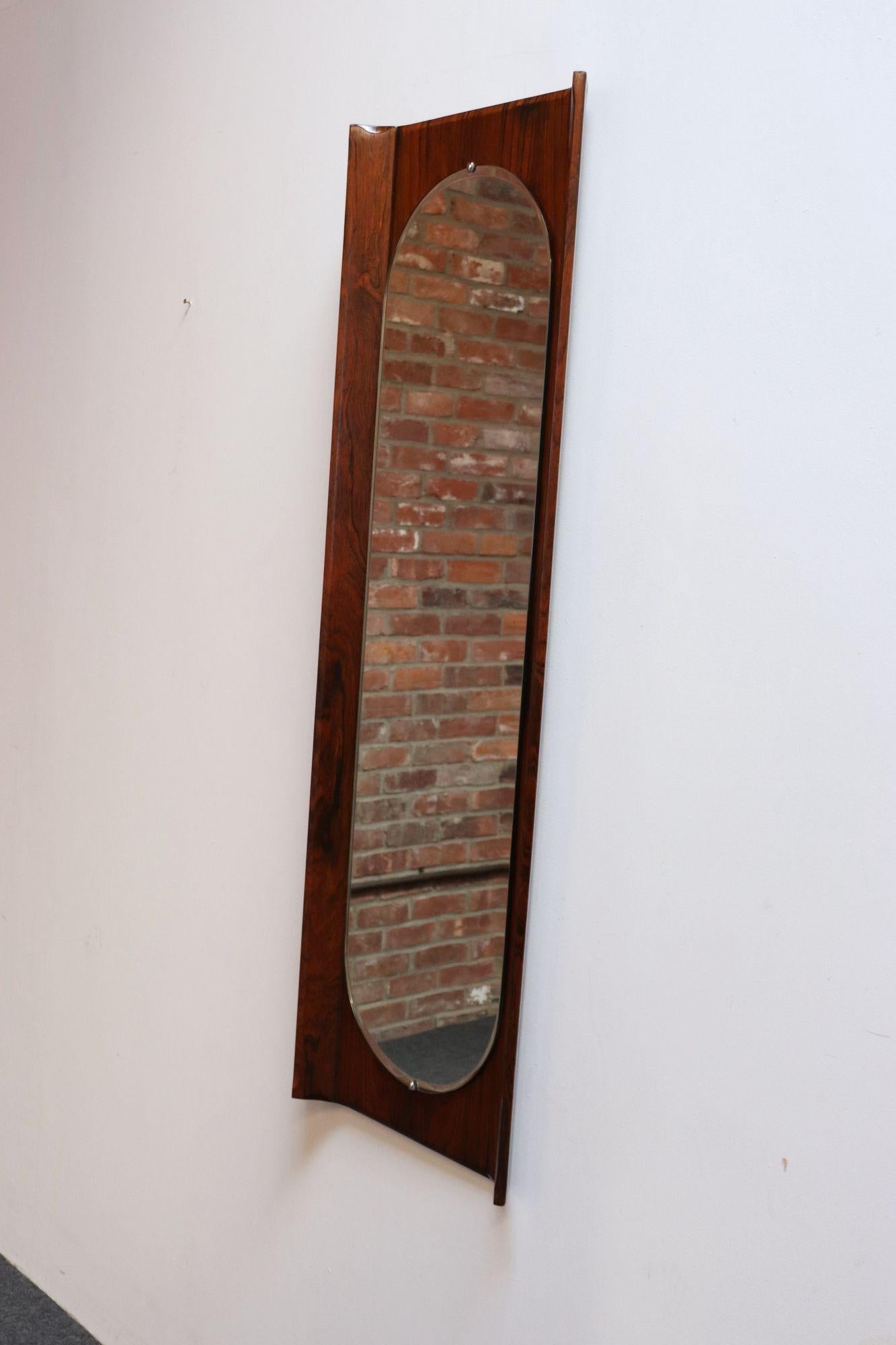 Sculptural mirror designed by Donati for Stil Glass (ca. 1960s, Italy).
Composed of an inset ellipse/oval mirror glass panel housed within a rosewood frame whose sides angle inward.
Excellent, vintage condition (no flaws to the glass, and the