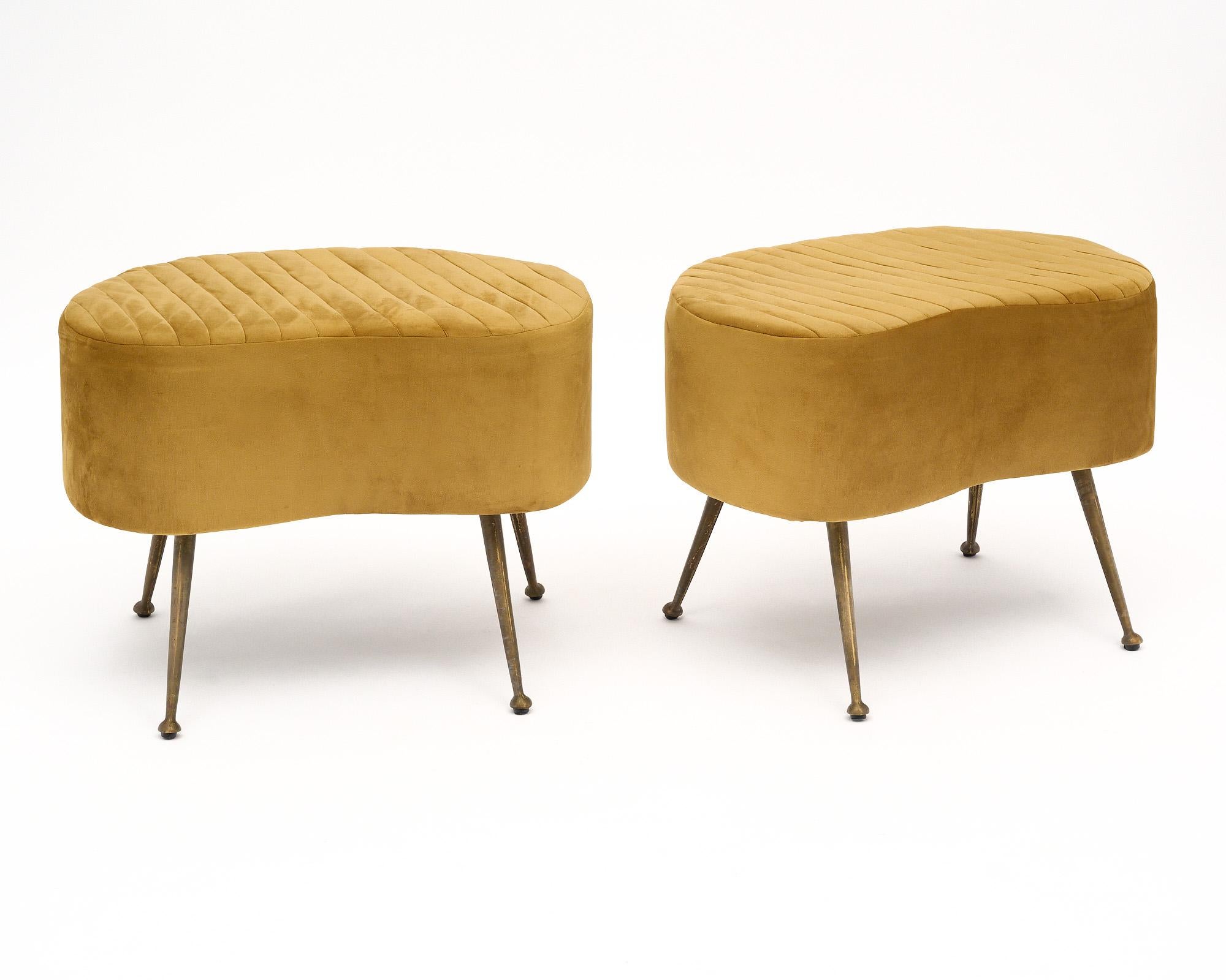 Pair of Italian vintage benches with flaring brass legs. We love the unique and striking curved shape of the seats and the quintessential Italian mid-century details. They have been newly upholstered in a gold mico fiber fabric with a quilted top.
