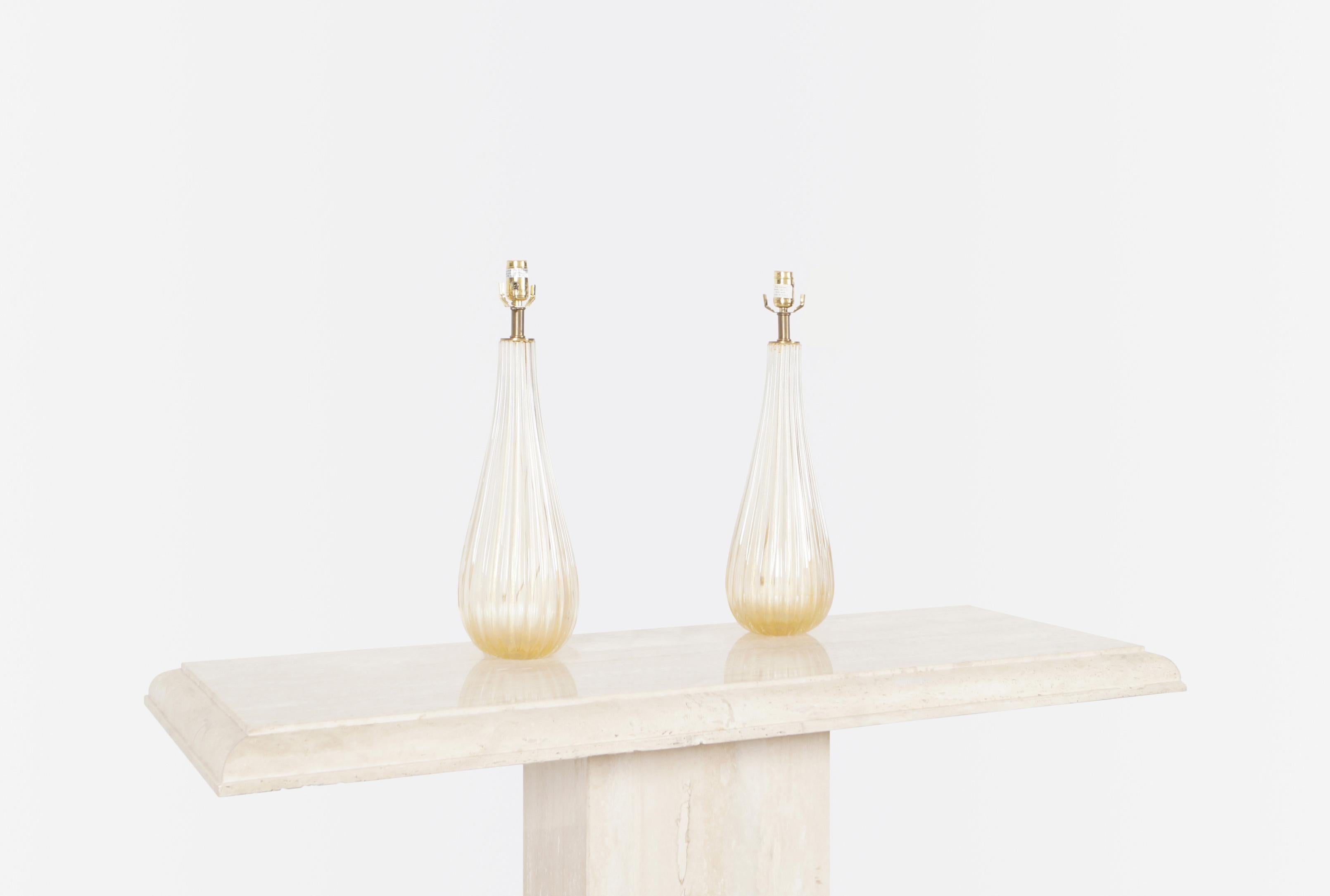 A pair of elegant vintage modernist Murano lamps manufactured in Italy, circa 1960s. These lamps have the shape of a water drop, that when illuminated, turns into a beautiful color. Reflecting through their bodies is a trace of gold flakes that give