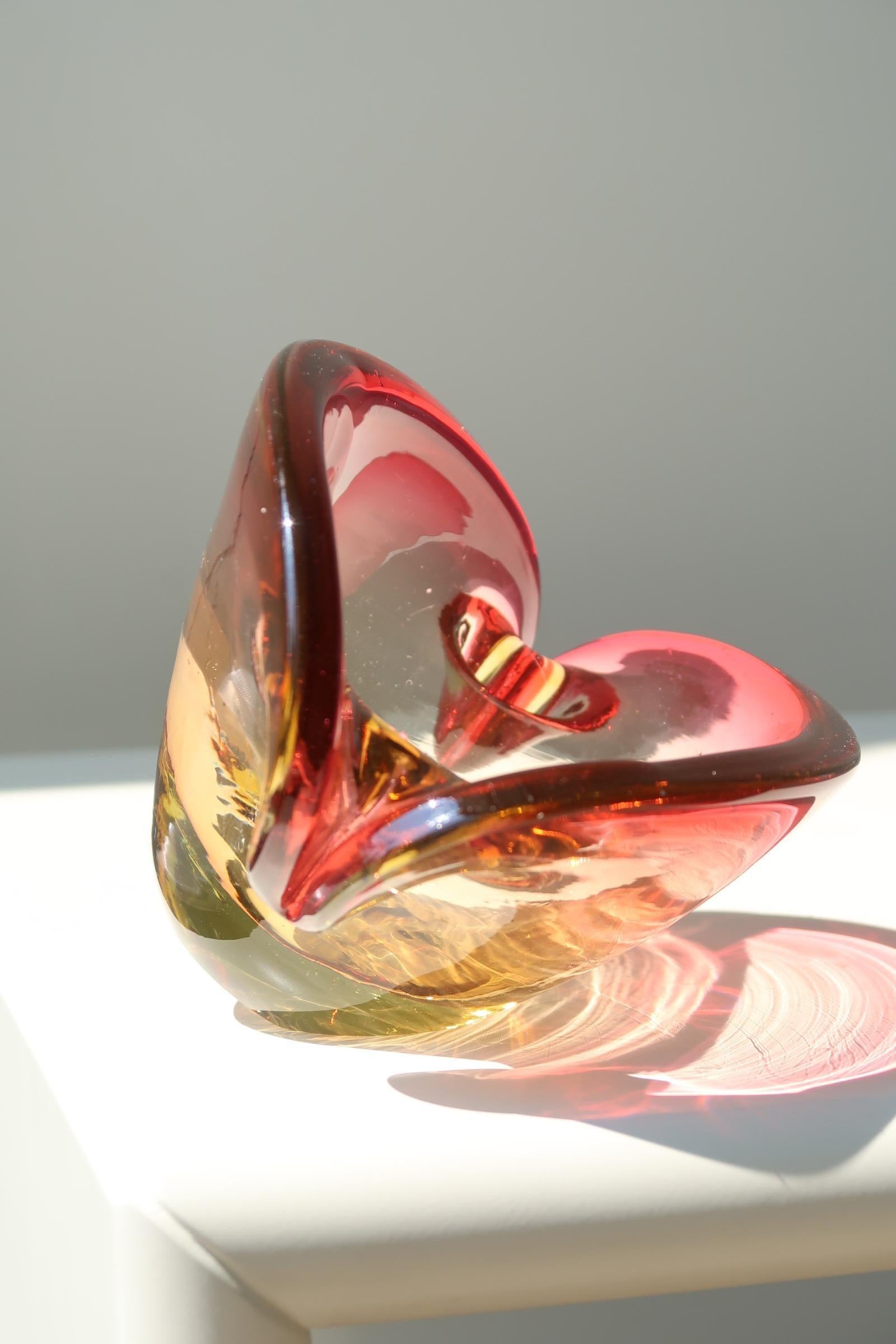 Vintage Murano clam bowl, mouth-blown in the Sommerso technique in red and yellow transparent glass. The clam has two bases and can either stand upright or tip on its side. Parts of the original sticker are still visible. Has normal signs of use.